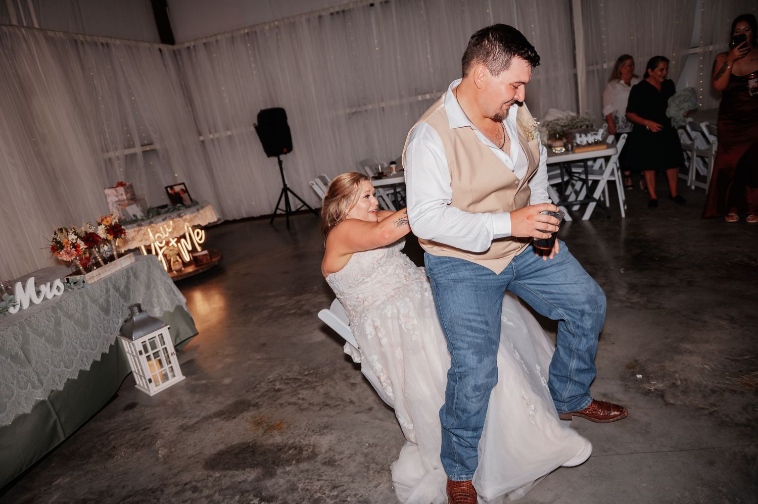 Bride and groom share a joyful dance at their wedding reception in a decorated indoor venue.