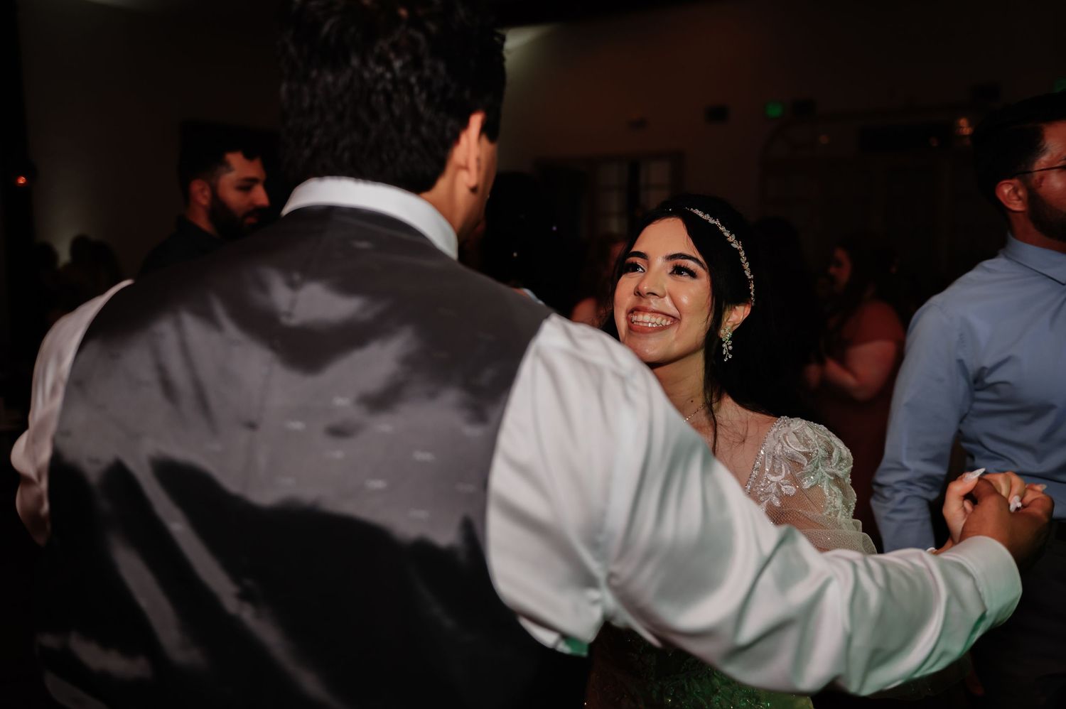Bride and groom share a romantic first dance at their wedding reception, surrounded by guests.