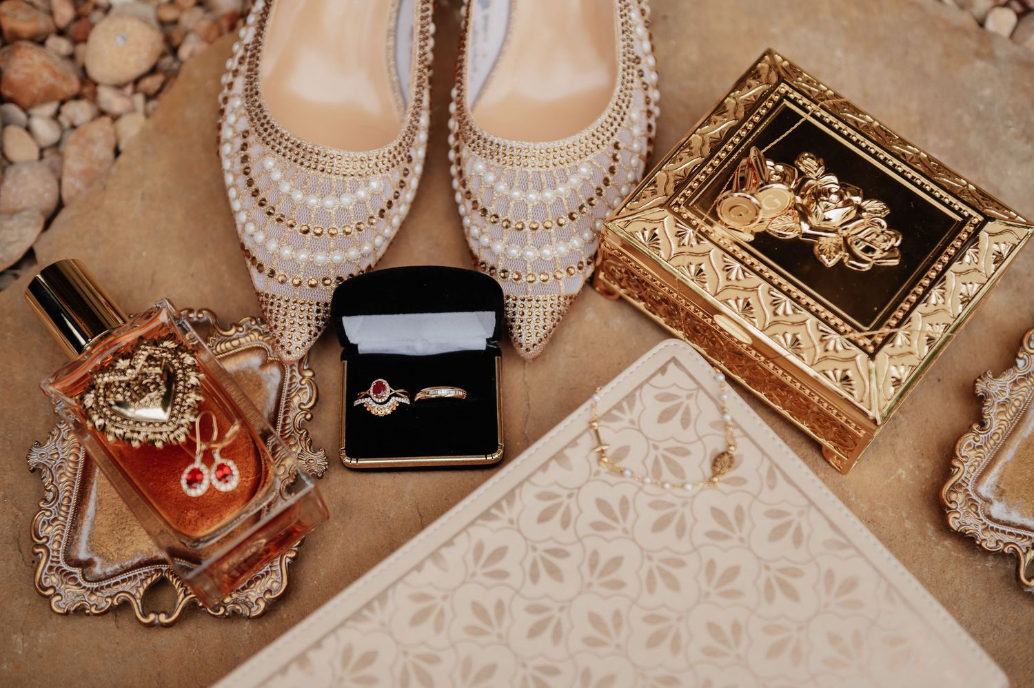Wedding flat lay with pearl heels, engagement ring, perfume, and ornate gold jewelry box.