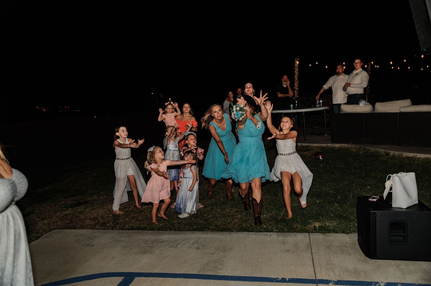 Group of girls dancing and celebrating outdoors at night during a wedding reception party.