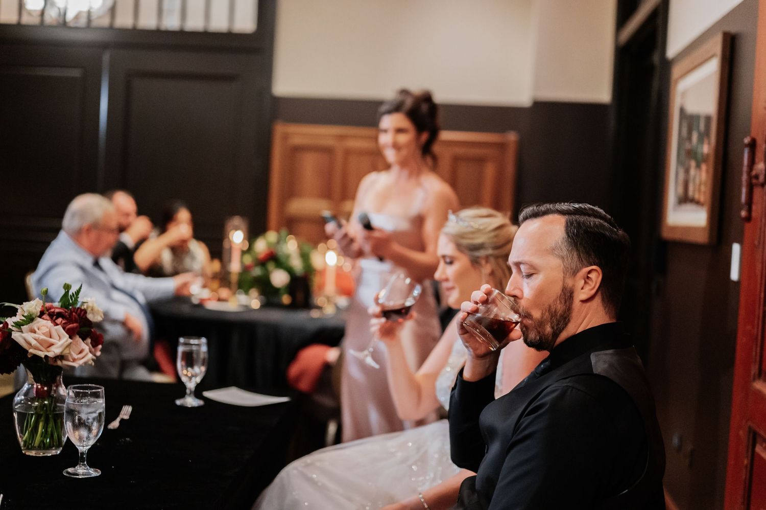 Guests enjoying wine at an elegant wedding reception dinner with candlelight and floral centerpieces.