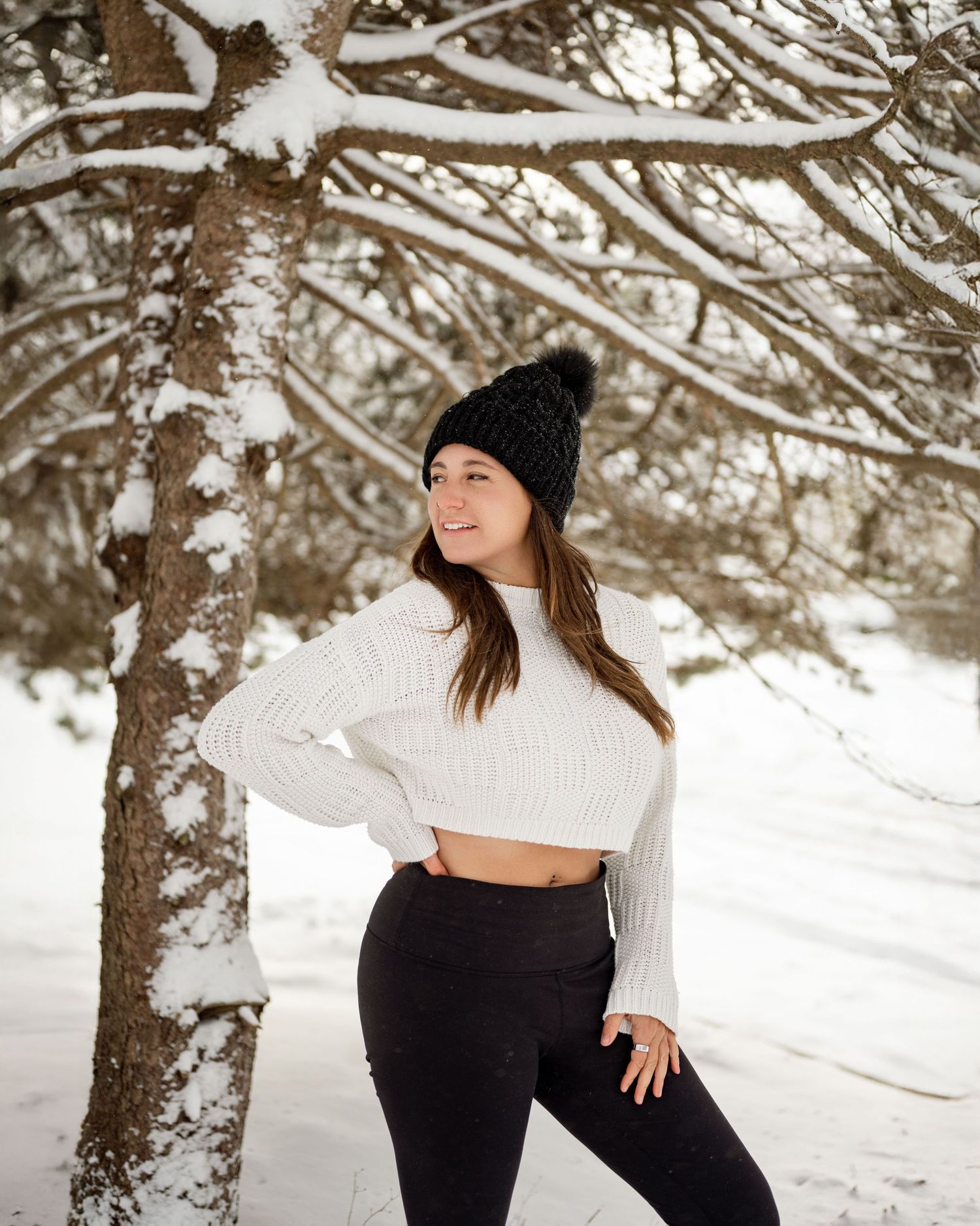Winter portrait photography session in a snowy forest setting with snow-covered tree branches.