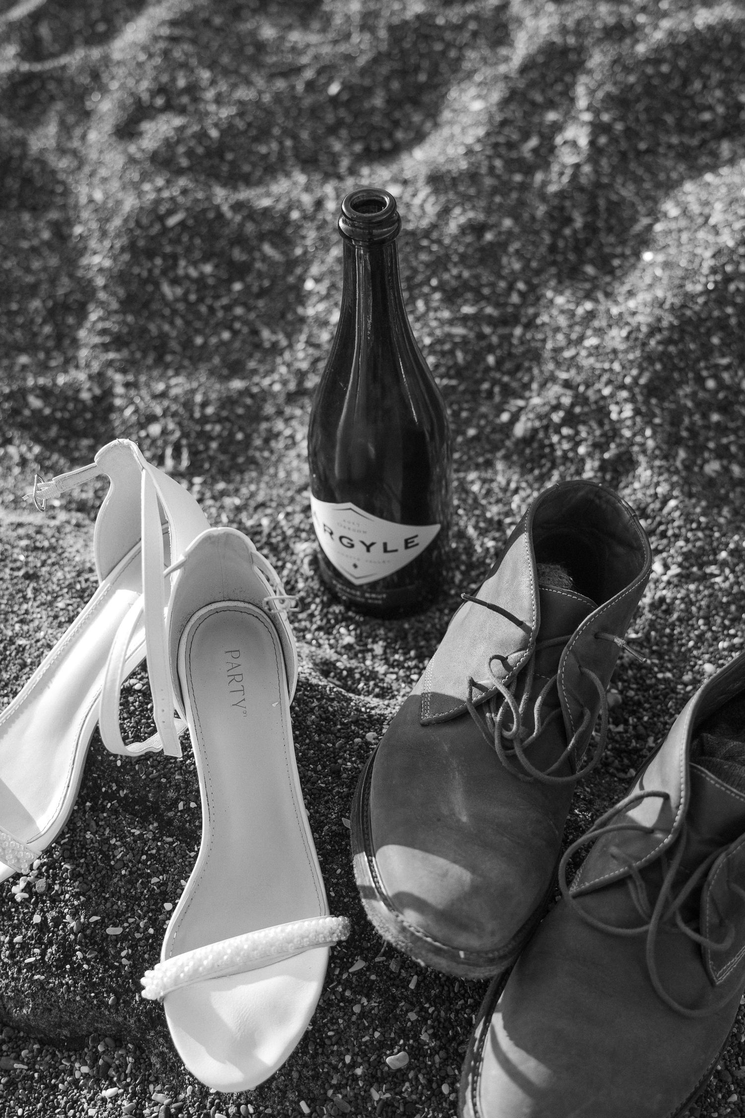 Wedding shoes arranged on textured surface - white bridal heels next to dark formal shoes.