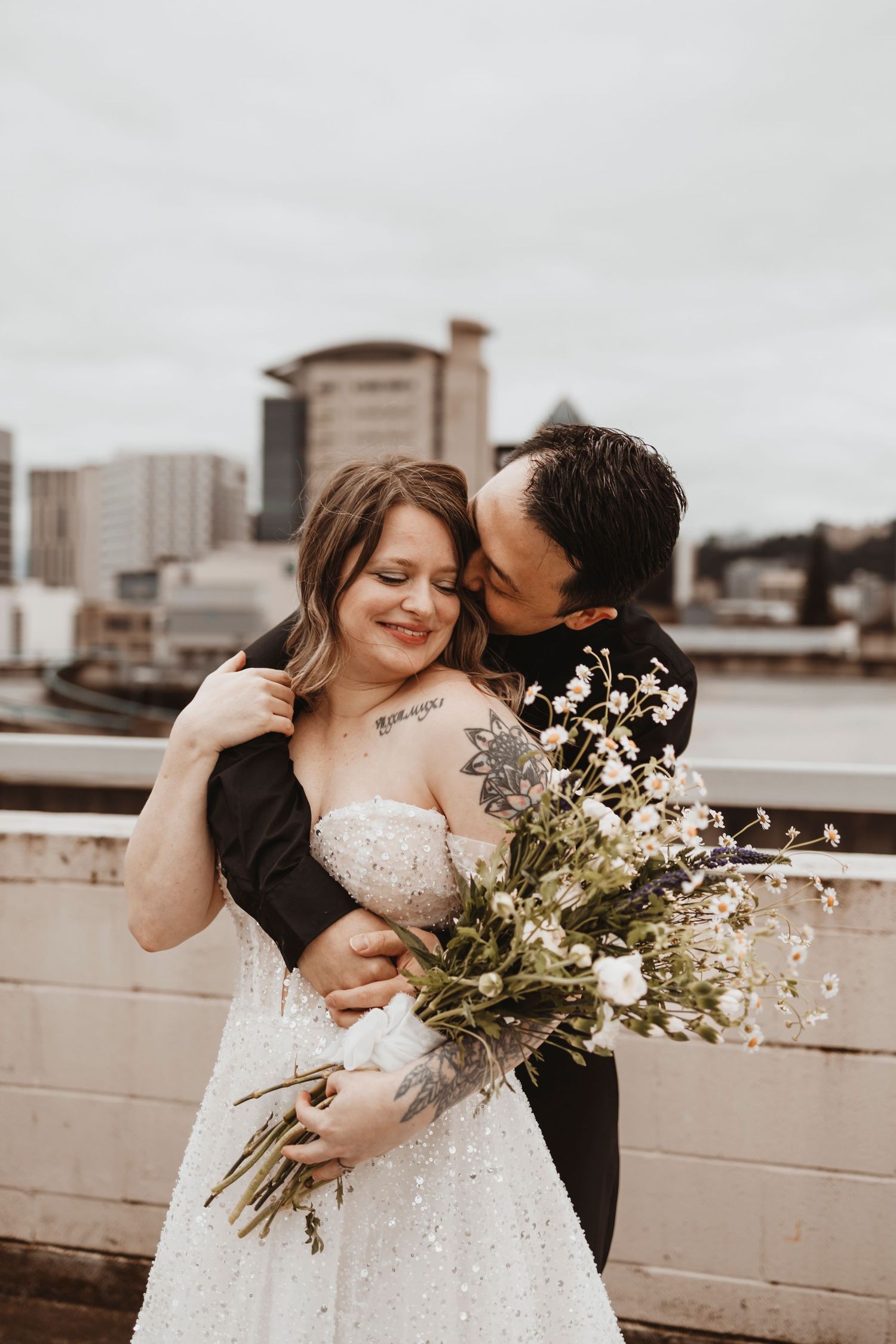 Urban rooftop wedding photos with white flowers and city buildings in background.