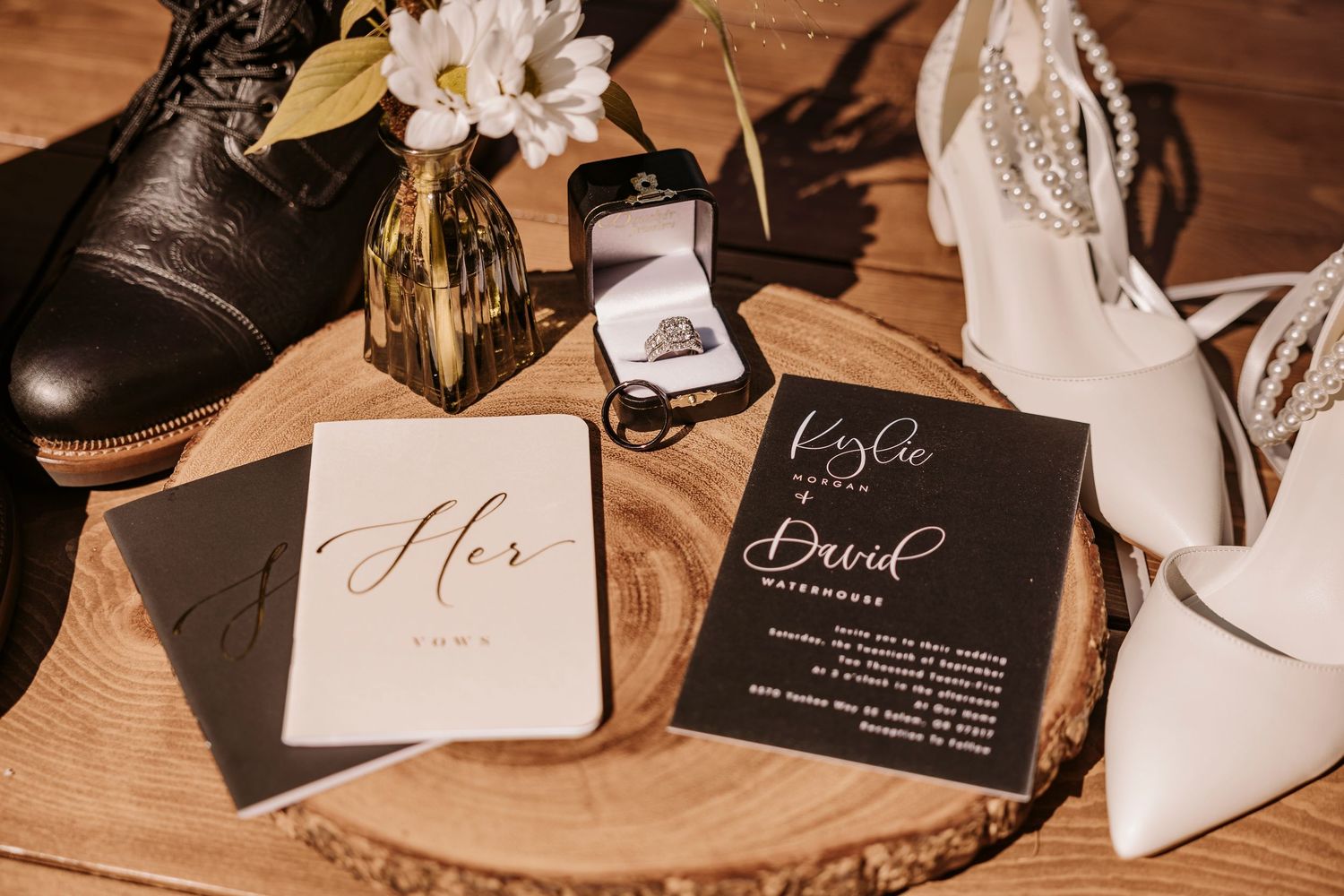 Wedding details including rings, invitation cards and bridal shoes arranged on wooden surface.