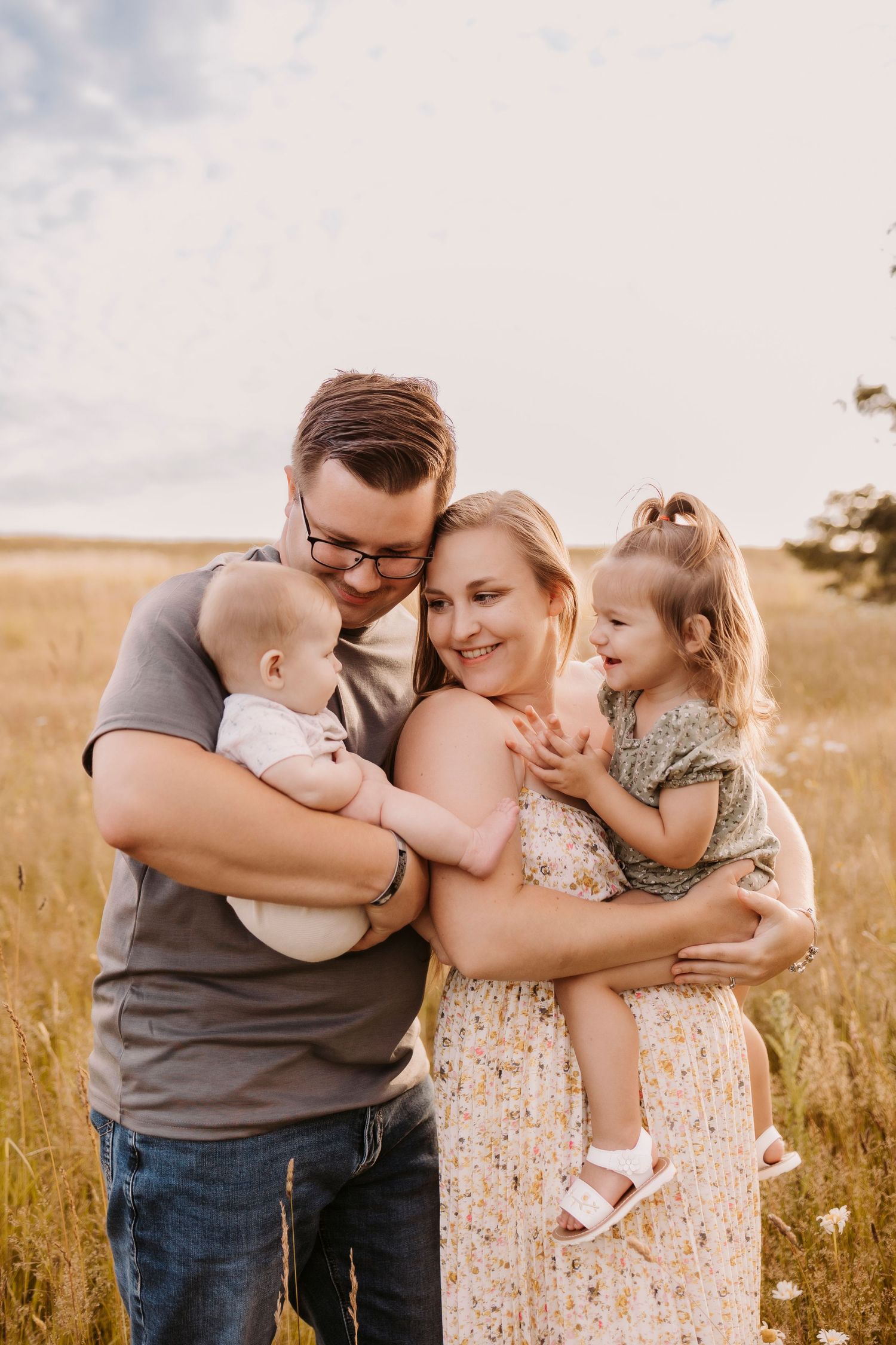 Family embracing in golden field during sunset photoshoot.