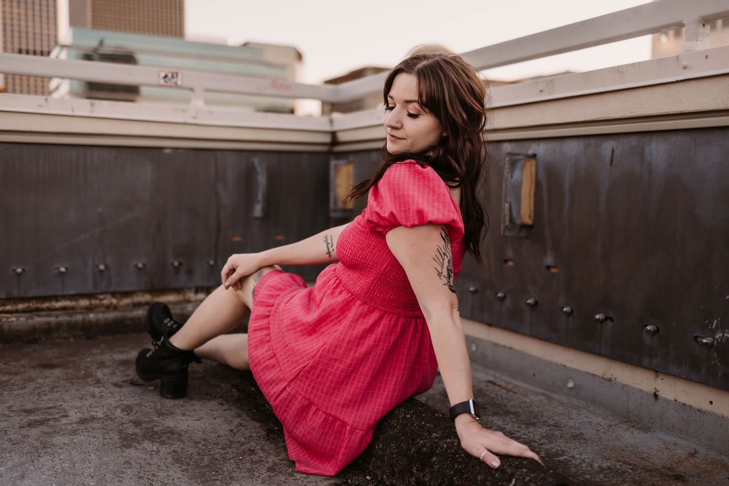 Artistic pose in a red dress on an urban rooftop with dramatic lighting.