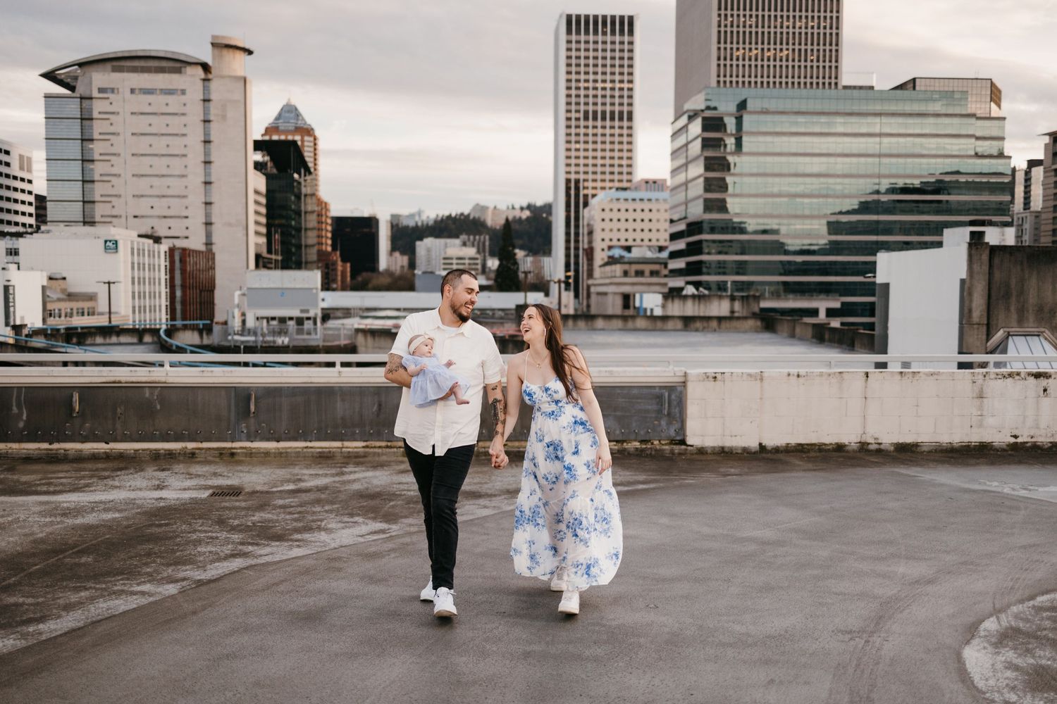 Wide angle shots of couple on industrial rooftop with downtown Portland buildings.