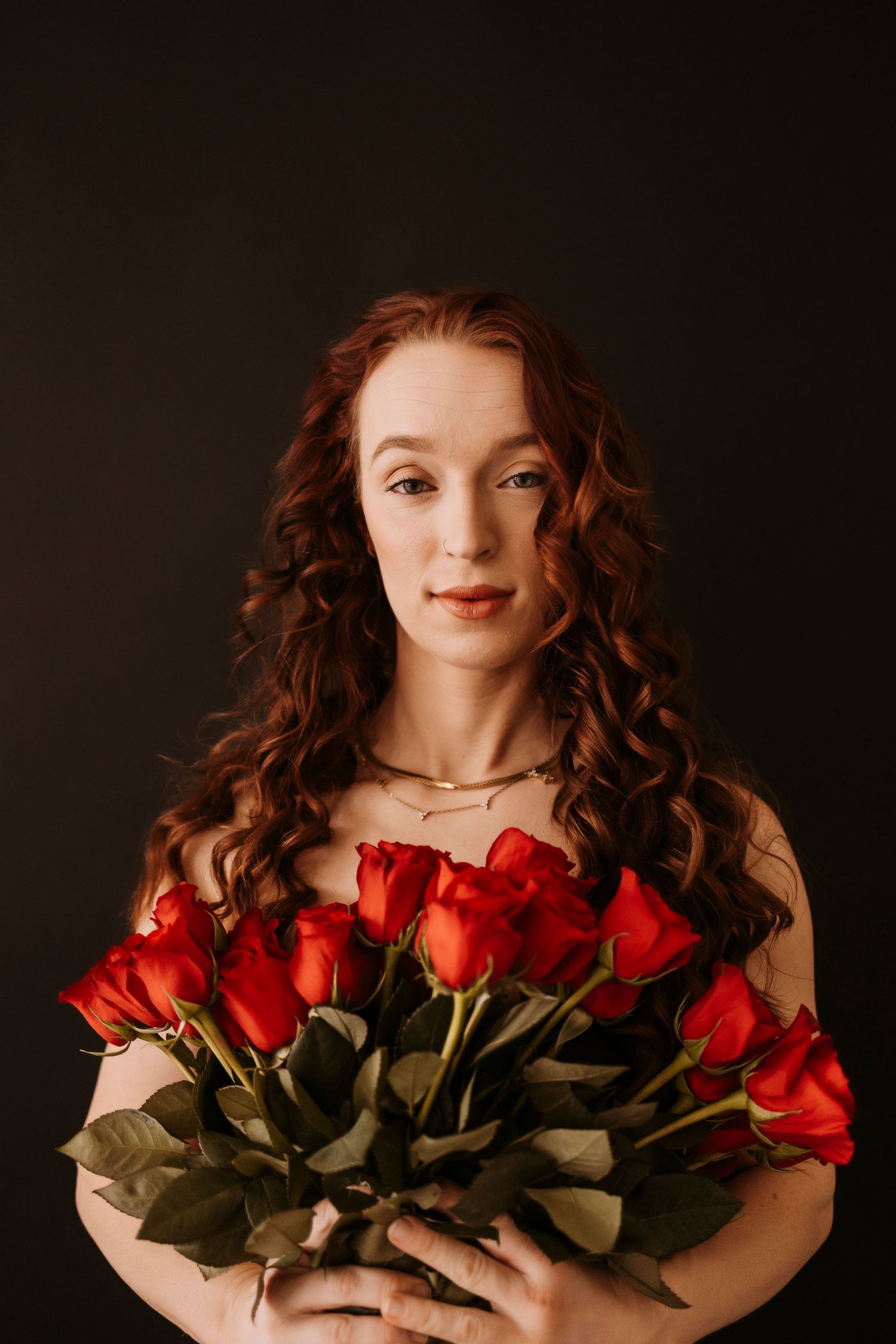 Studio portrait with dramatic lighting featuring a bouquet of vibrant red roses.