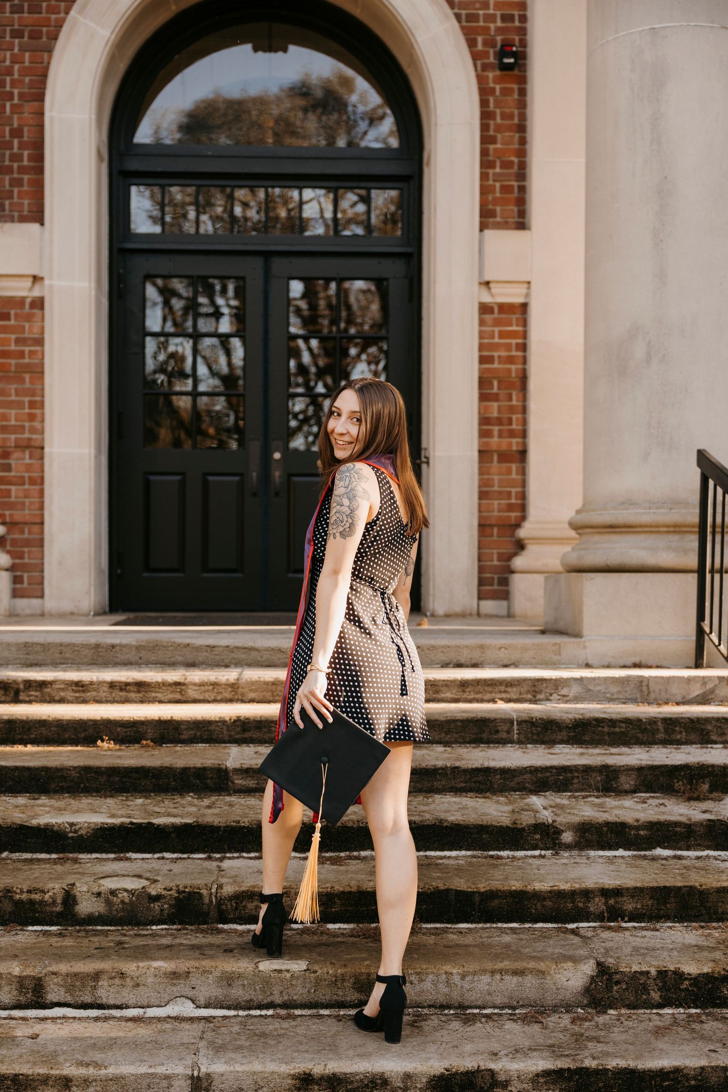 A graduation photoshoot on brick steps of a historic building with white columns.