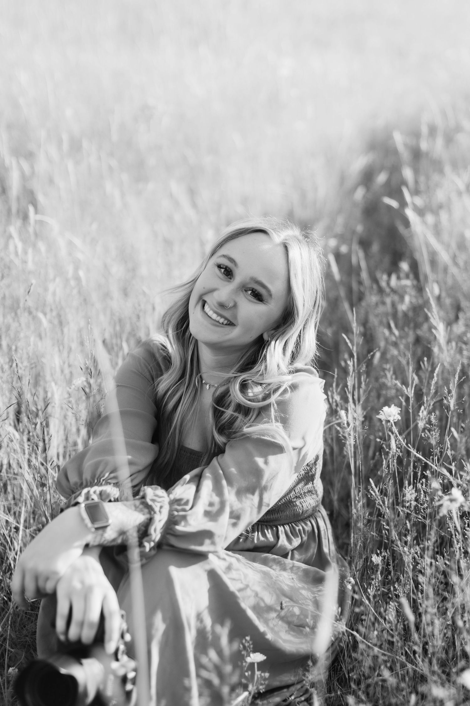 Black and white photos of someone lying in tall grass field with joyful expressions.