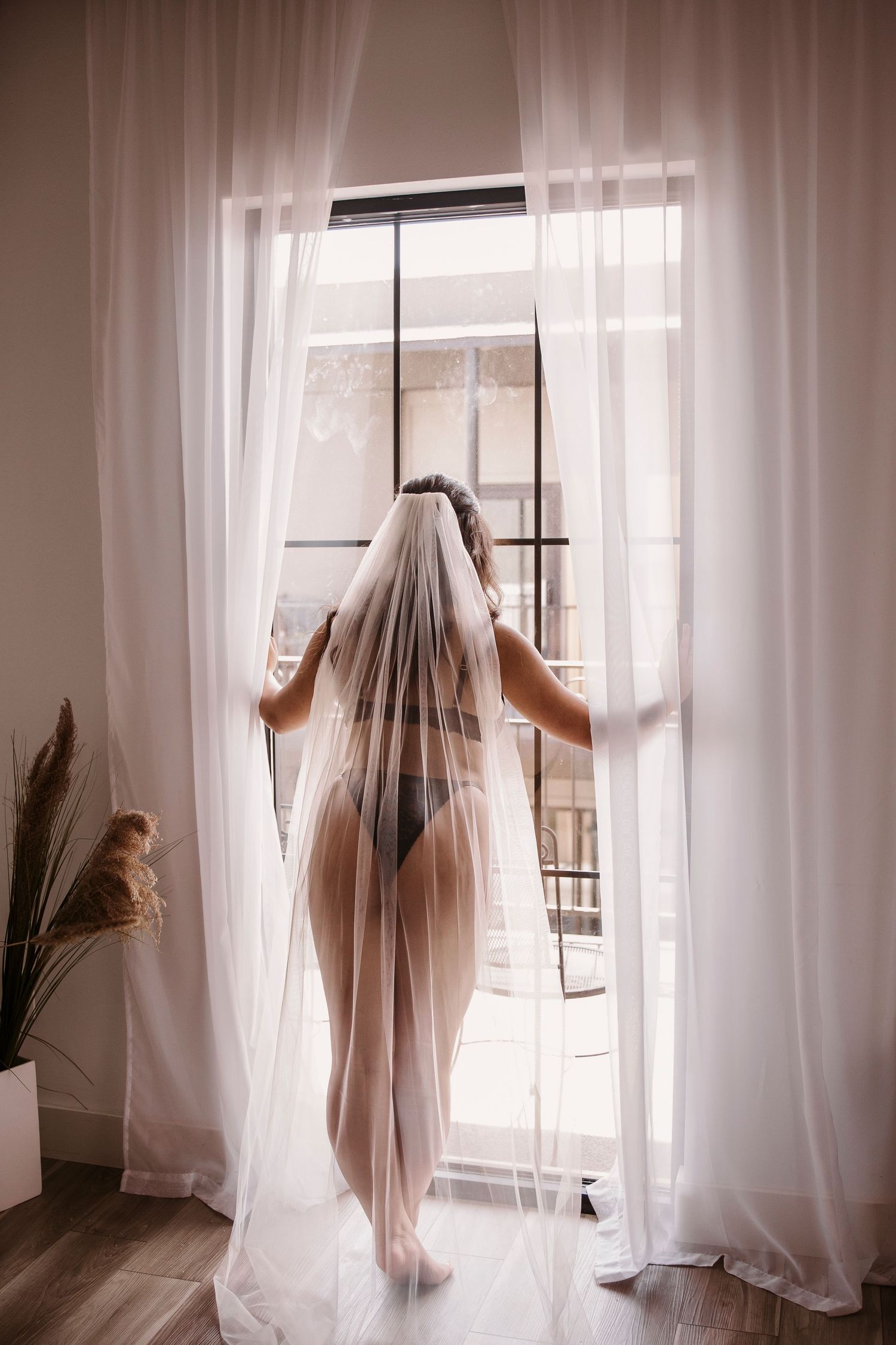 Silhouetted figure behind sheer white curtains in a bright window-lit room.