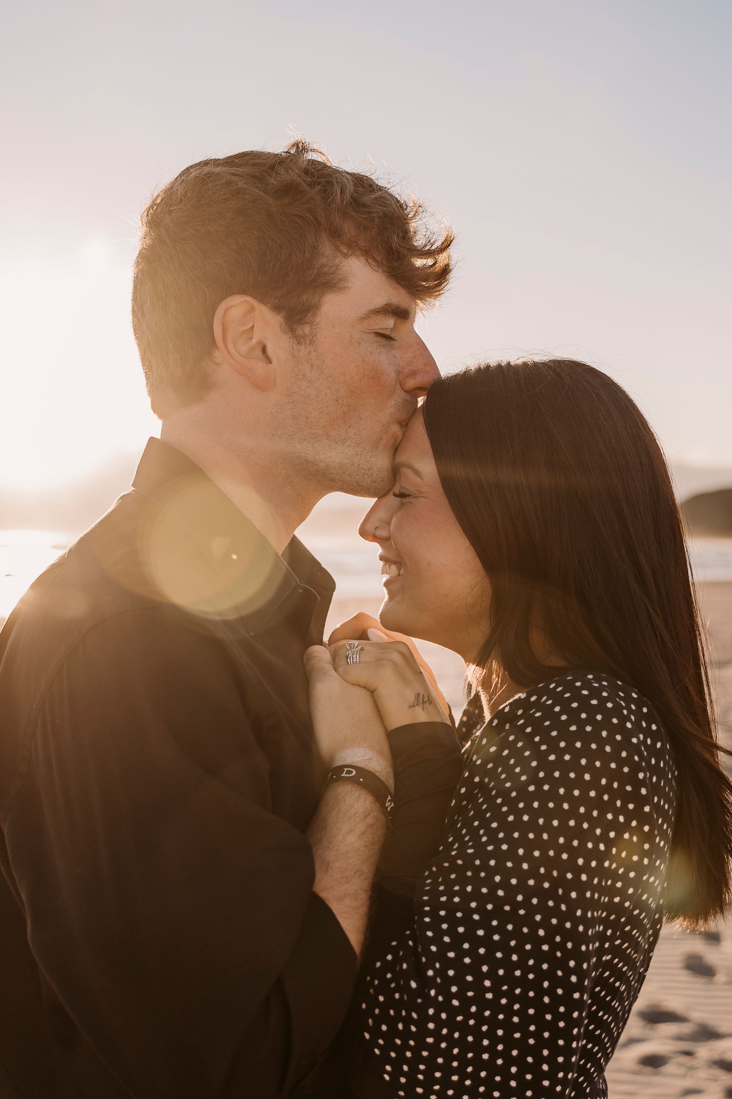 A tender moment between a couple during golden hour on a beach.