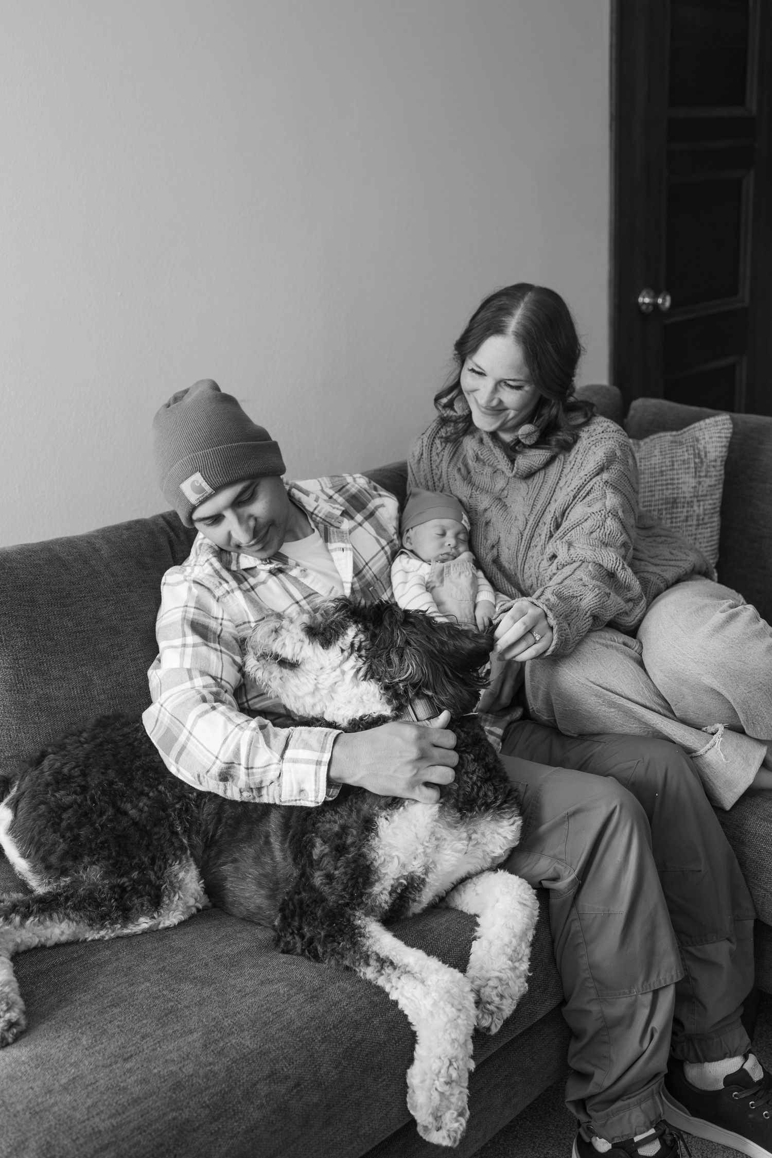 A family cuddles with their fluffy white dog on a comfortable grey couch.