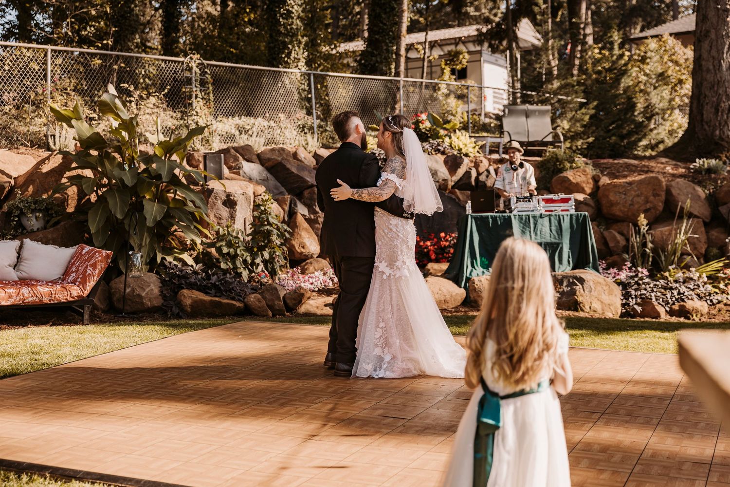 Wedding celebration in progress at a rustic outdoor venue with wooden buildings and natural surroundings.