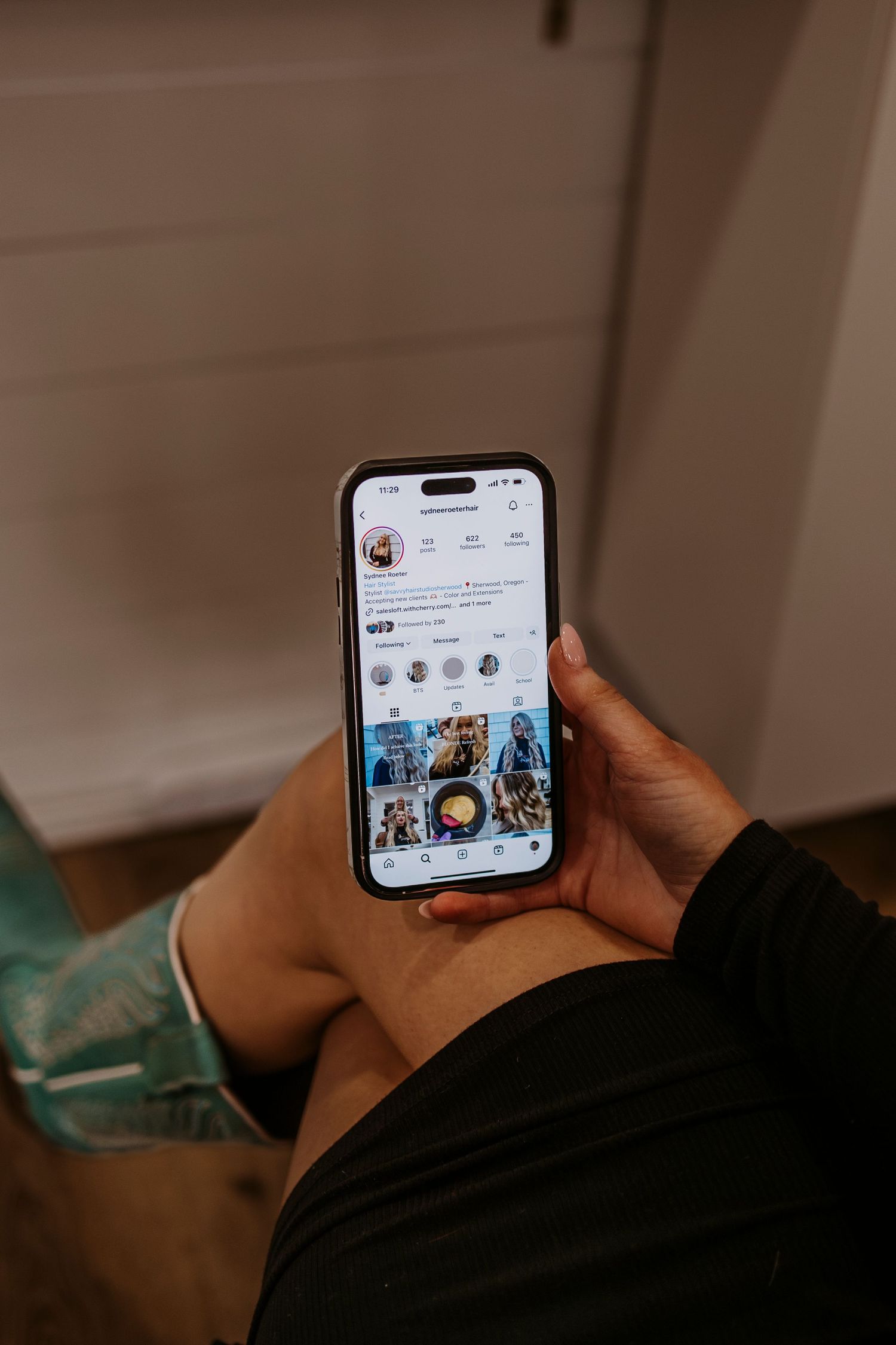Hands holding smartphone displaying social media feed in dim lighting.