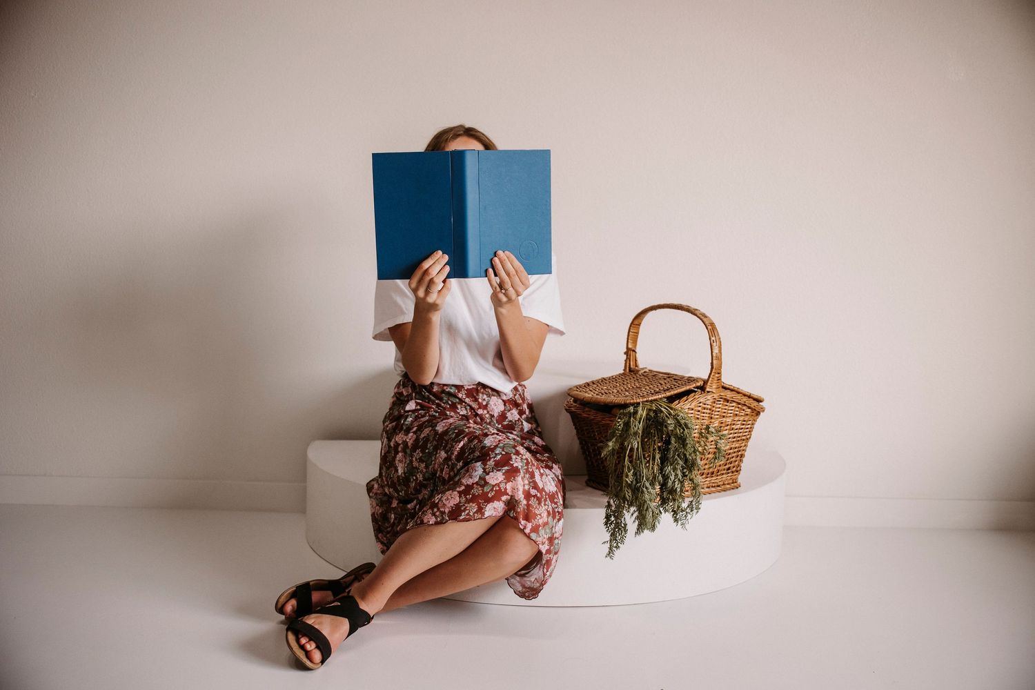 Minimalist product photography setup with blue book and woven basket against white background.