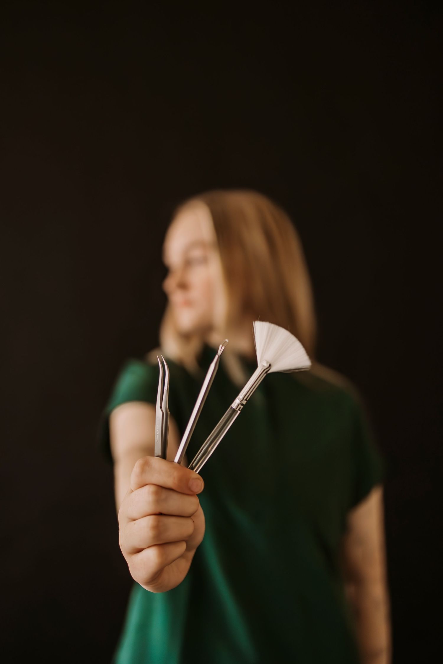 Close-up shot of hands holding professional beauty tools against dark background.