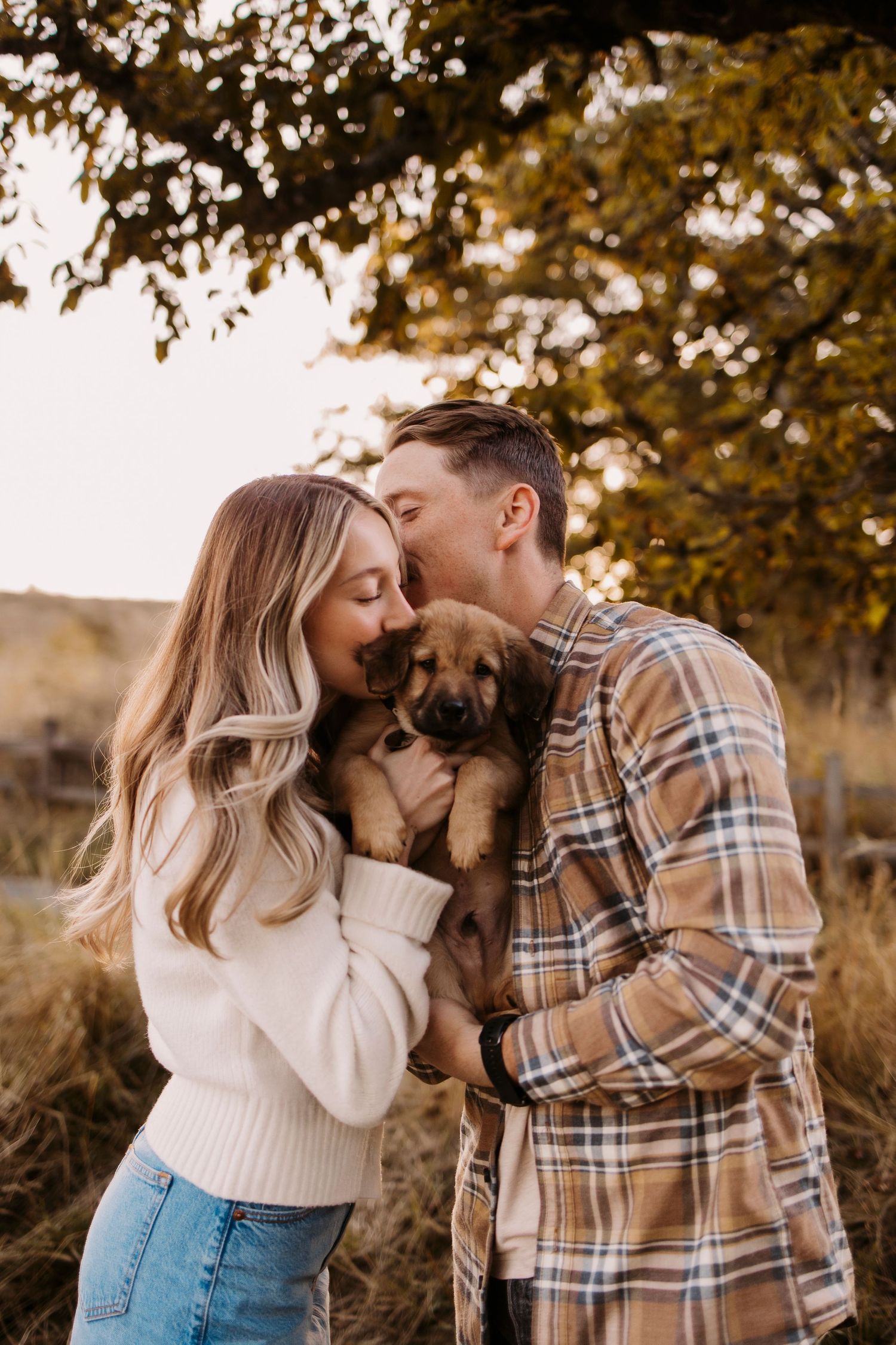 Romantic autumn photoshoot with couple and their small dog in warm fall colors.