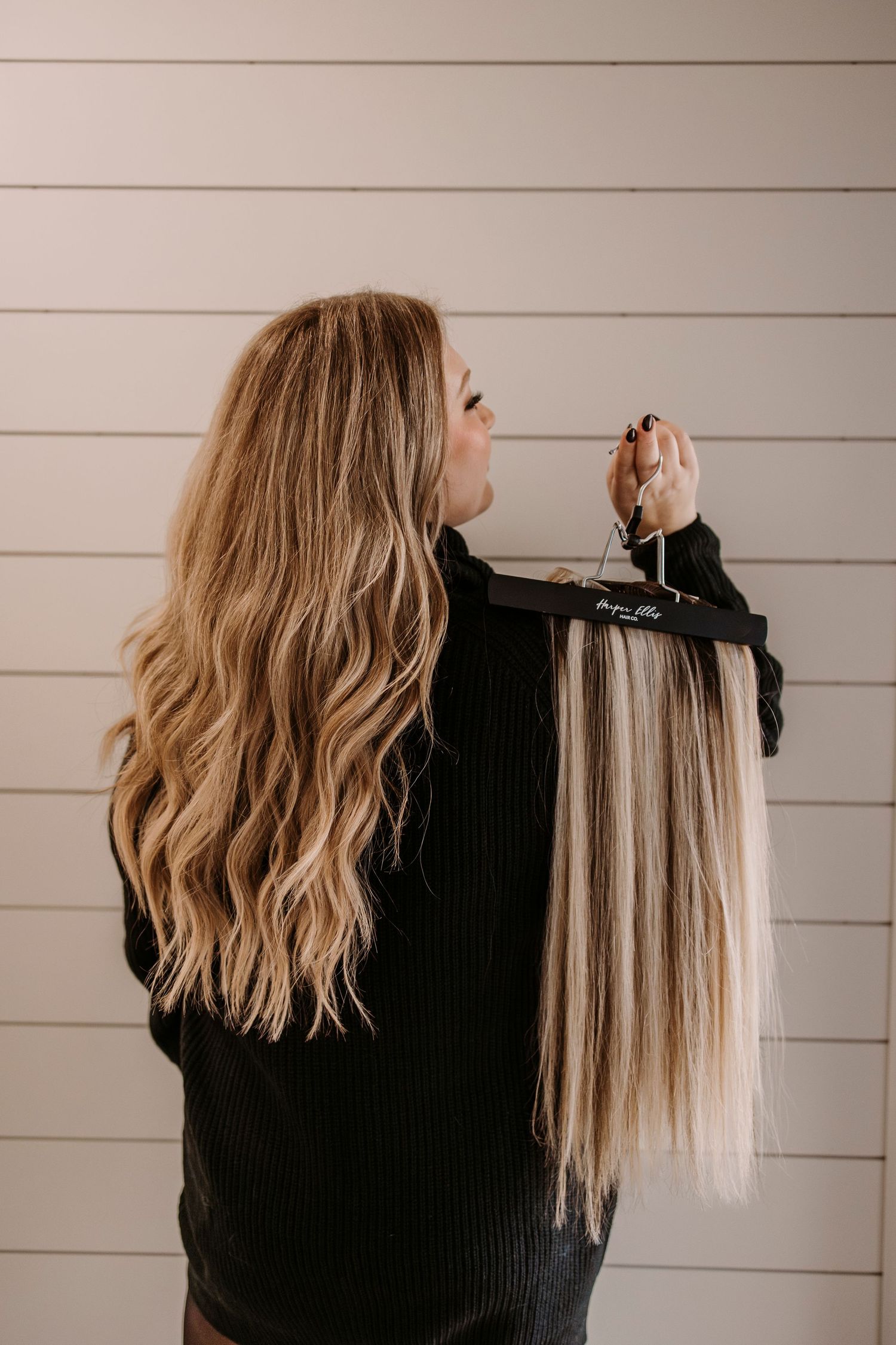 Hair extensions being displayed and sorted by color against white wall background.