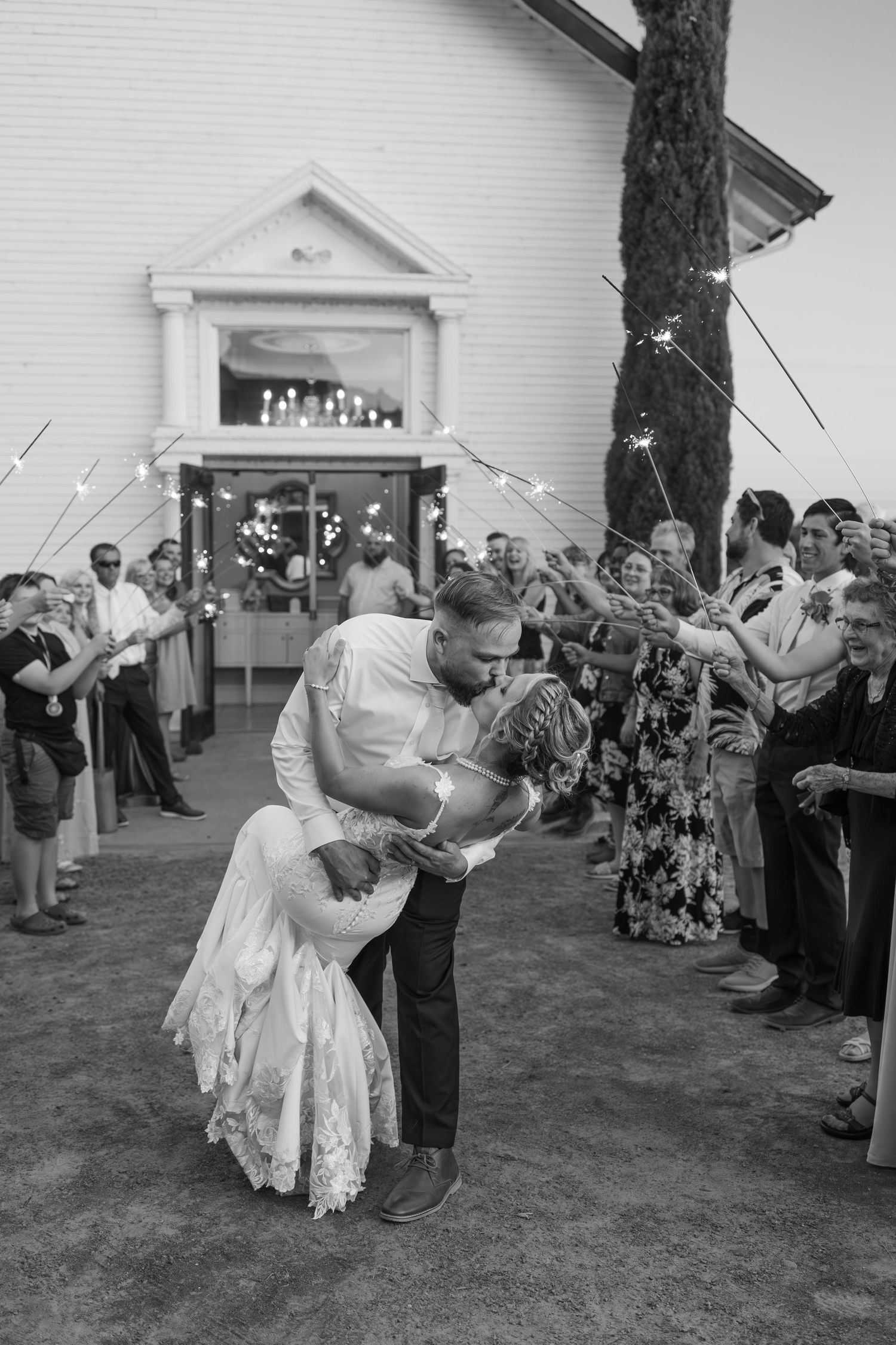 Black and white photo of couple sharing romantic dip during first dance at outdoor wedding reception.