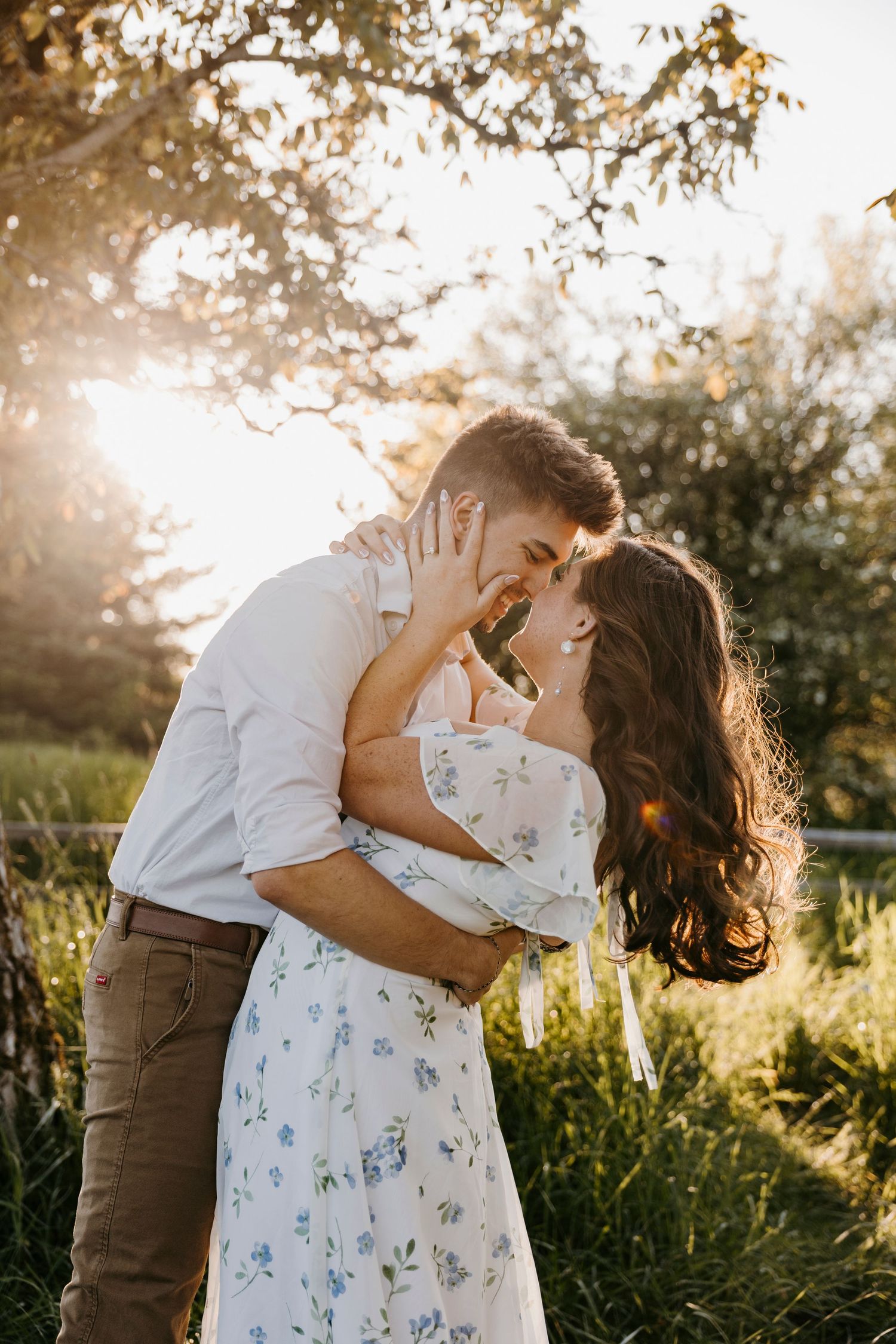 Intimate couple photos in floral dress against golden sunset light.