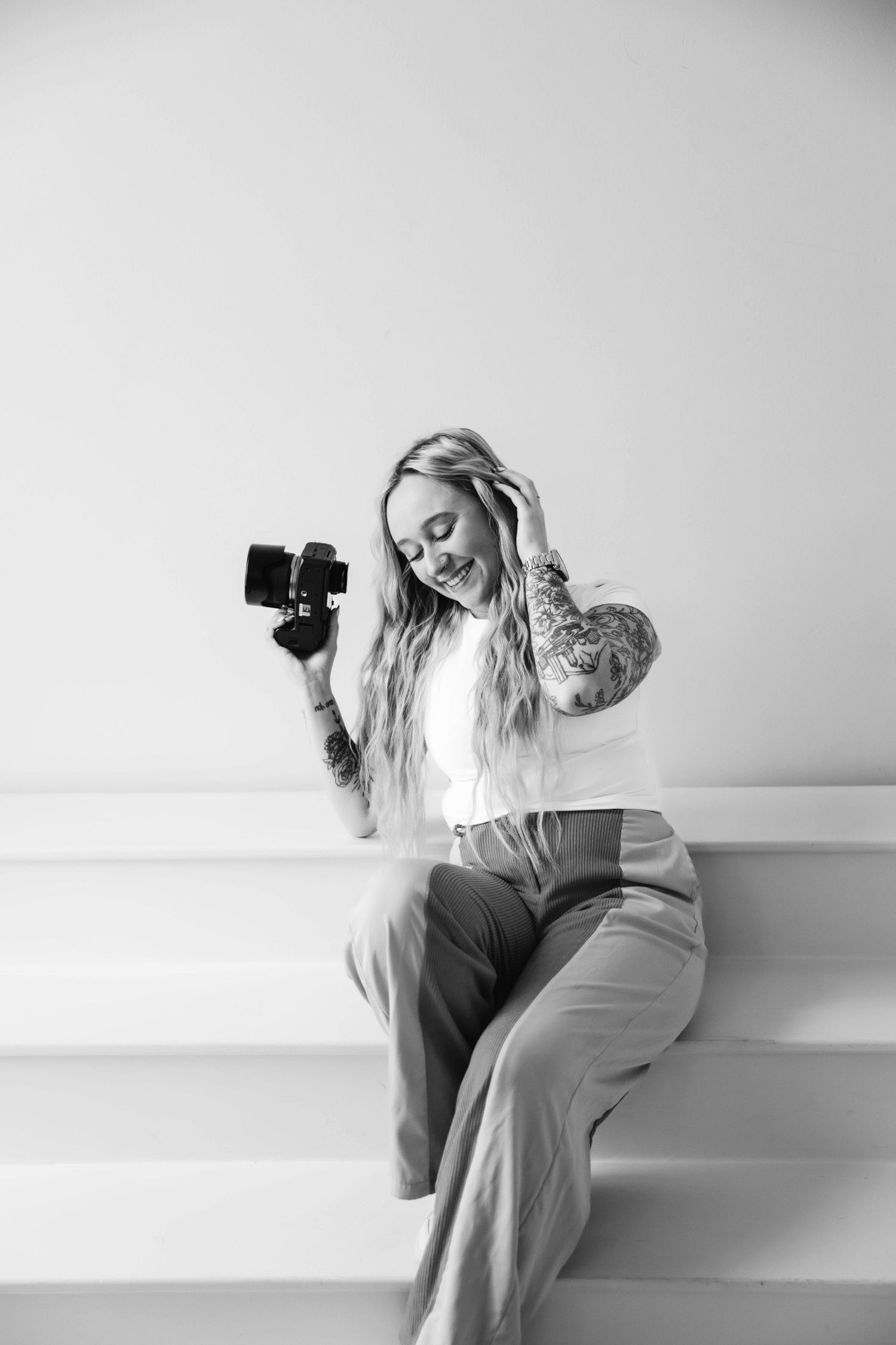 Black and white series of photographer posing with camera on white steps.