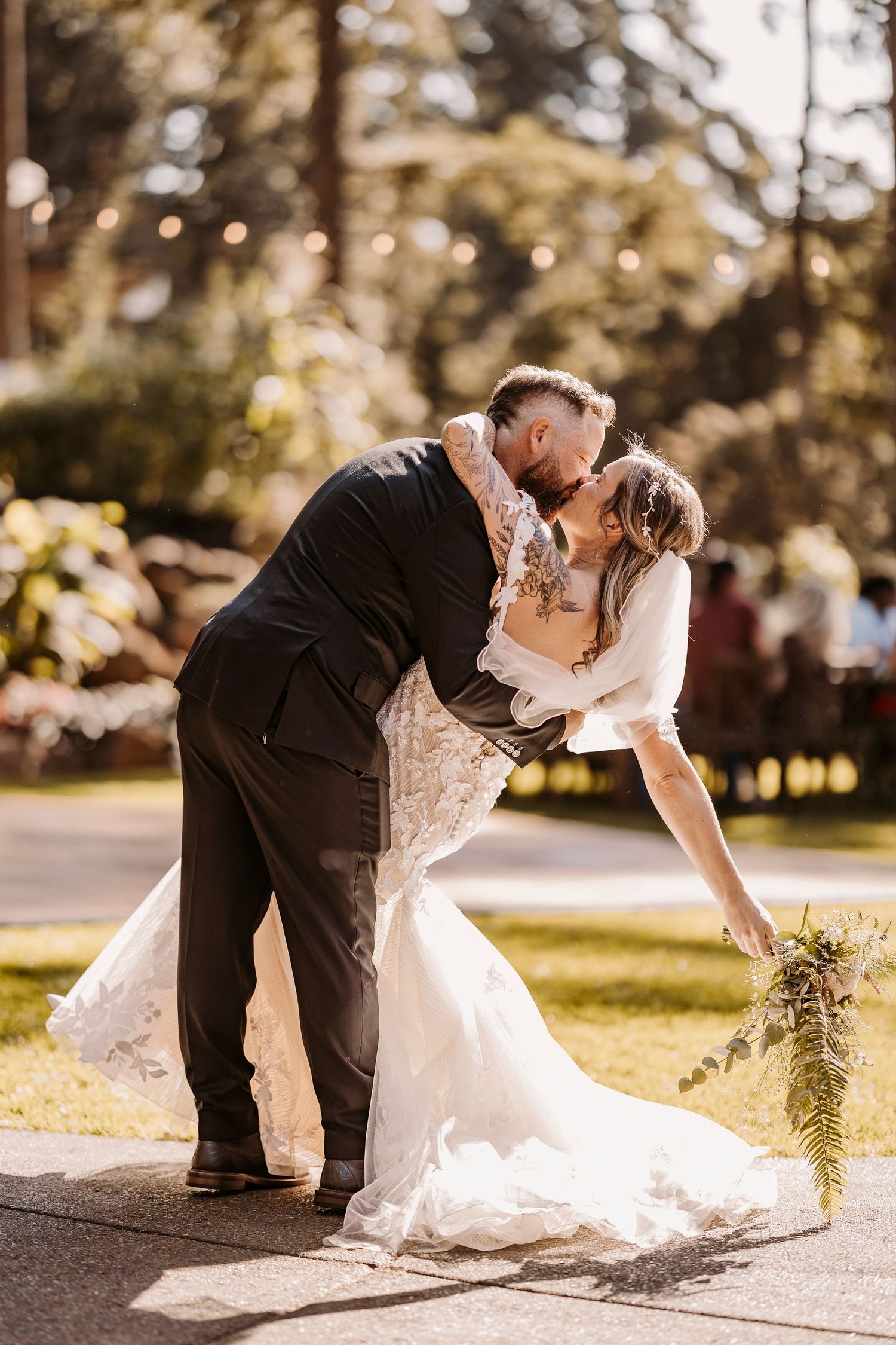 Wedding couple shares romantic dip poses outdoors in formal attire.