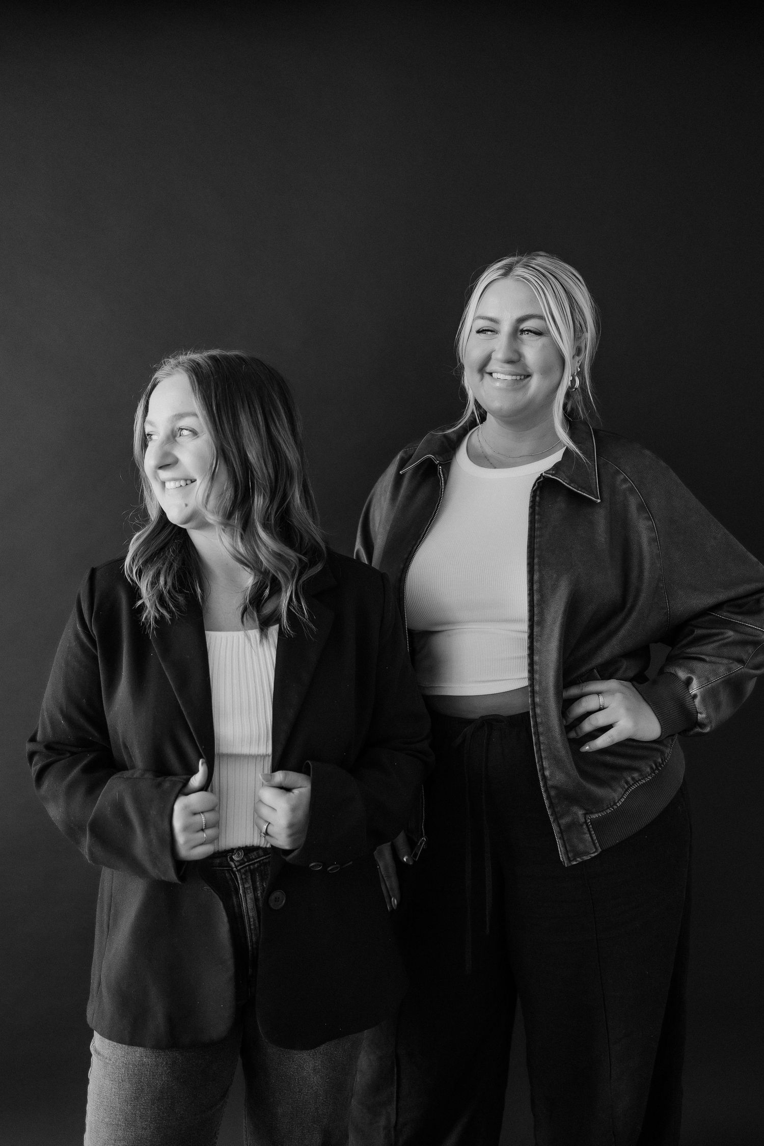 Black and white portrait of friends laughing together in casual denim outfits.