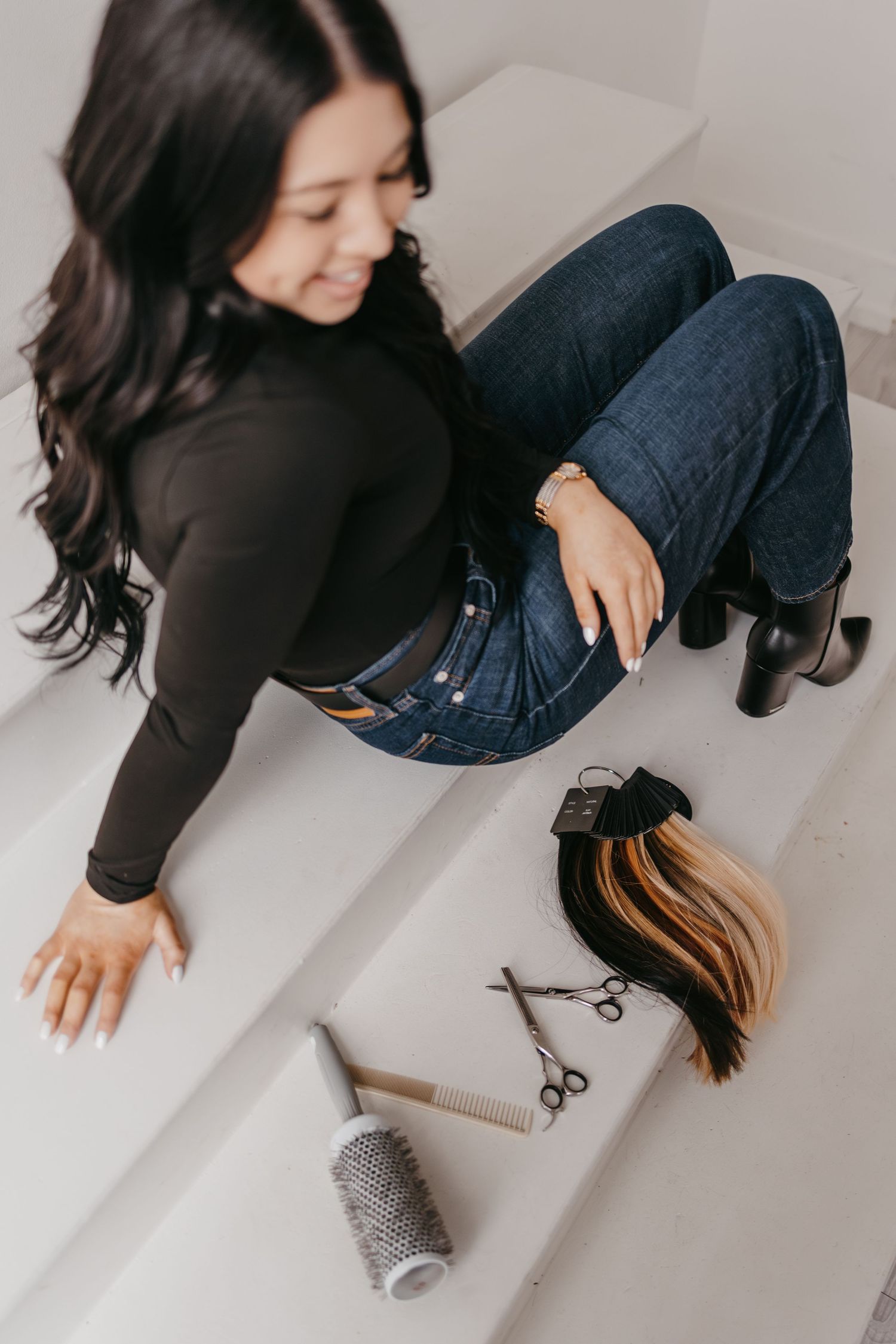 Overhead view of hair styling tools and extensions arranged on white surface.