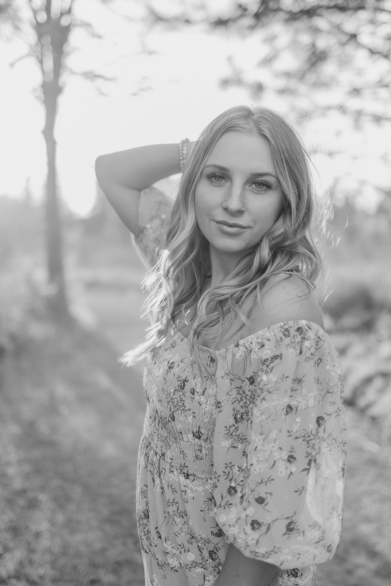 Black and white portrait in floral dress with soft natural lighting outdoors.
