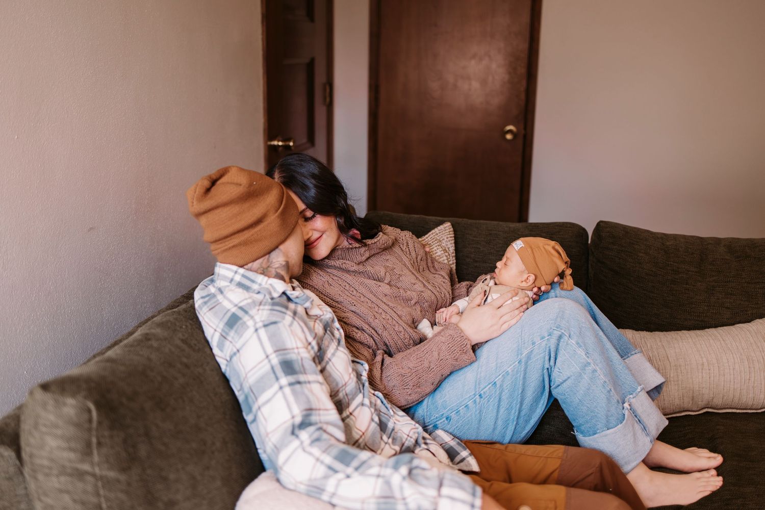 A cozy scene of people relaxing on a grey couch in a dimly lit room.