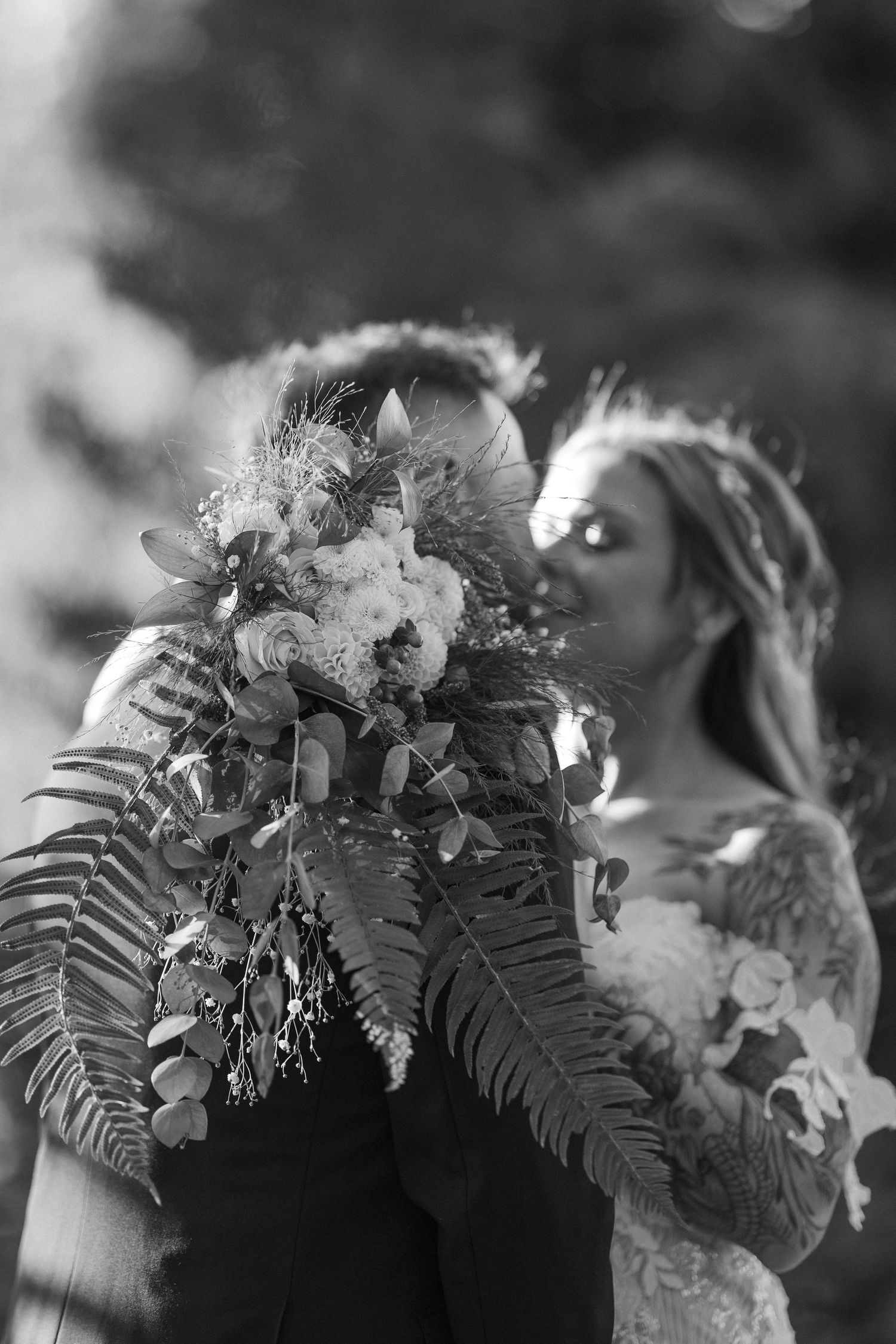Black and white photo of wedding floral arrangements with delicate ferns and blooms.