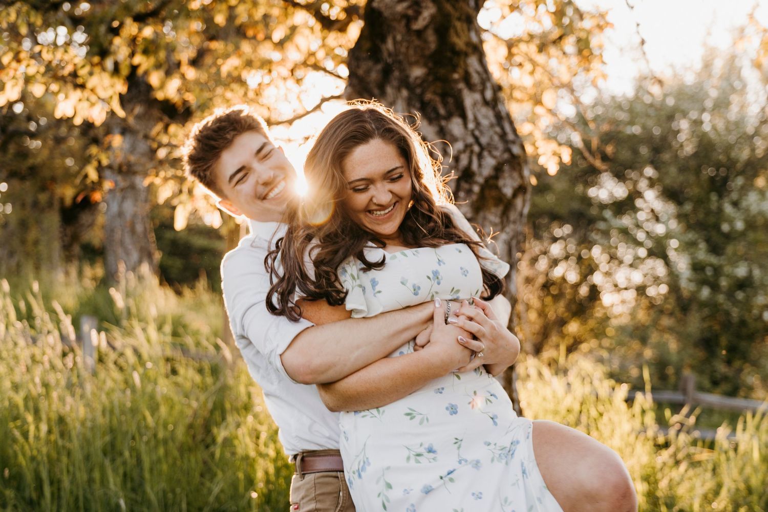 Couple embraces in sunlit garden during golden hour photoshoot.