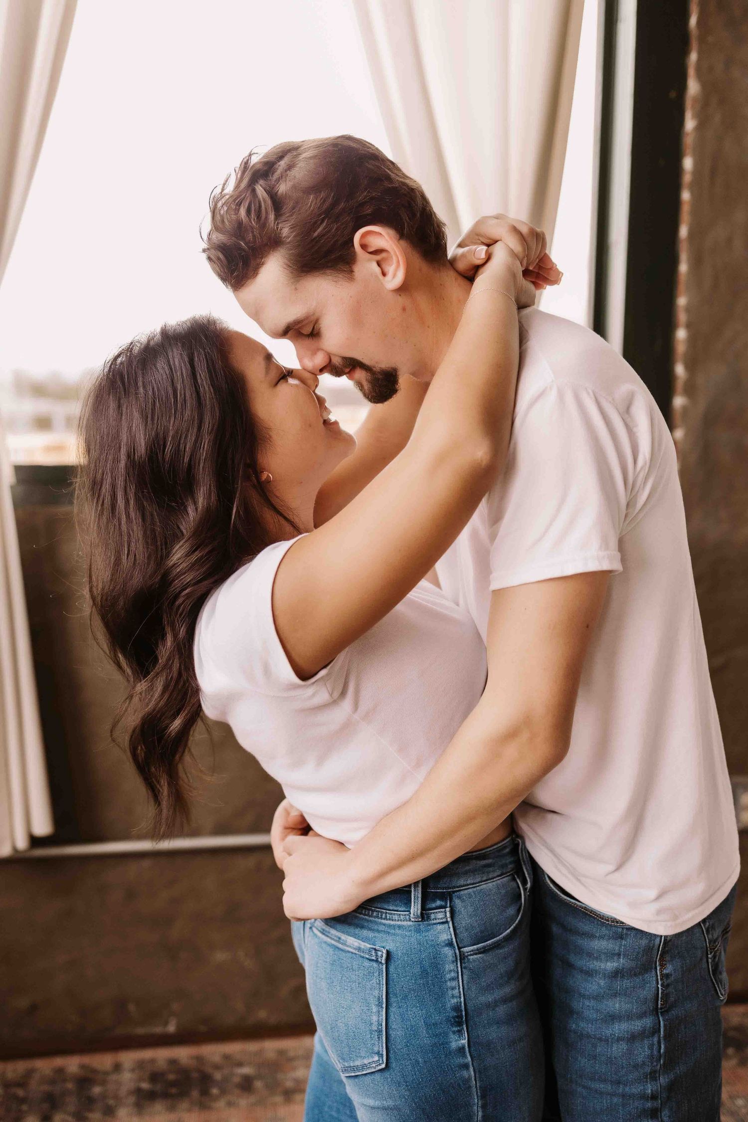 Romantic couple in matching white tops and jeans sharing an intimate moment.