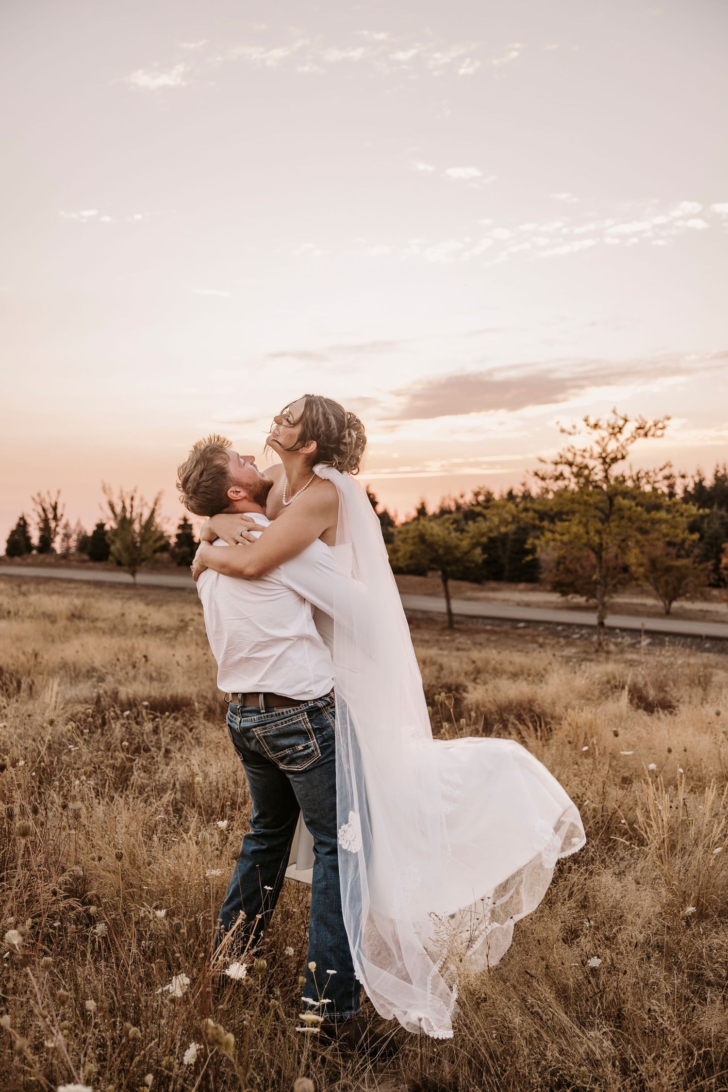 Couple dancing in a golden field at sunset during their wedding celebration.