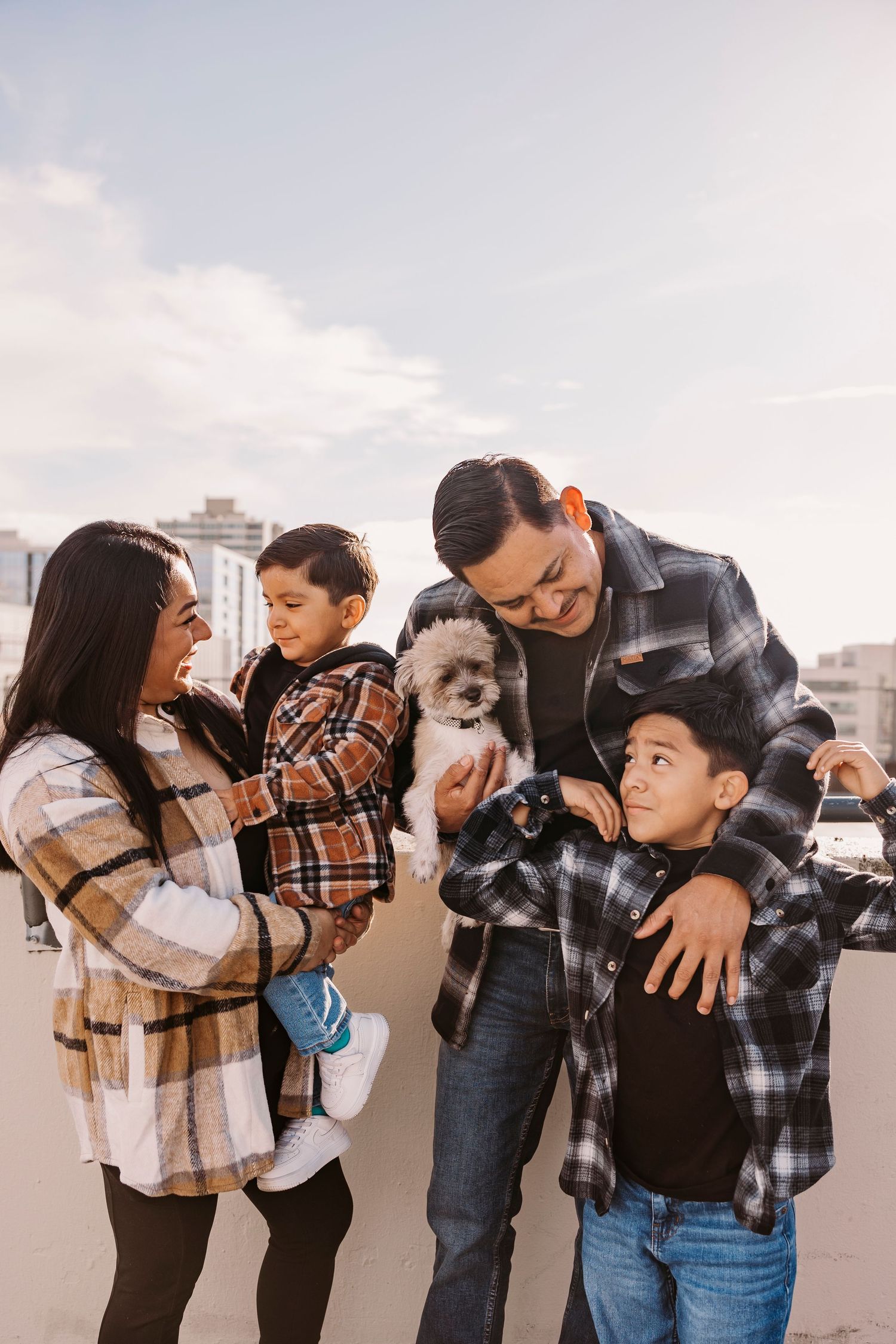 A family plays together with their small white dog on an outdoor patio.