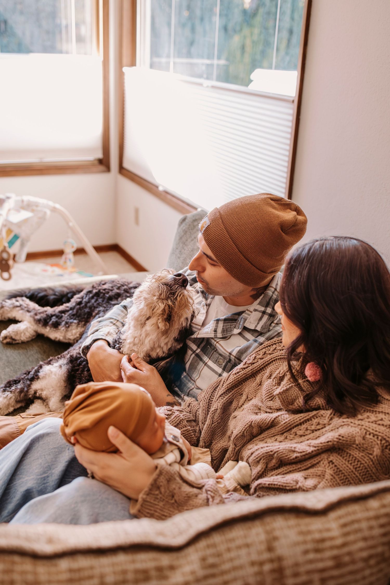 People relax together under cozy blankets by a bright window.