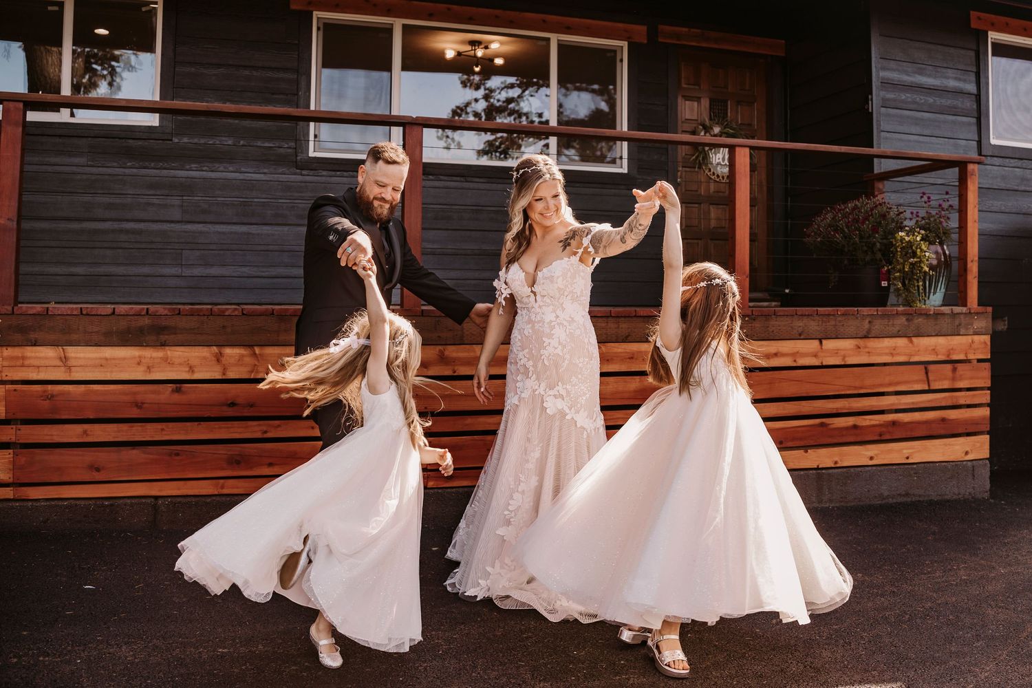 Wedding party dancing and twirling in white dresses inside a rustic wooden venue.
