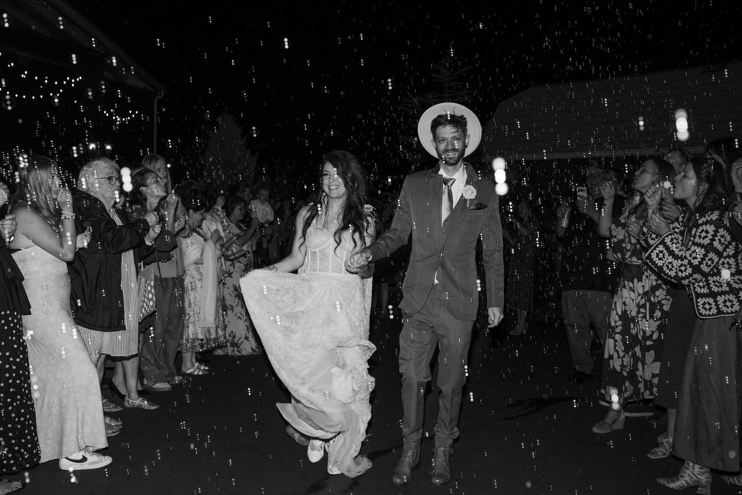 Wedding reception dance party with guests celebrating under twinkling lights at night.