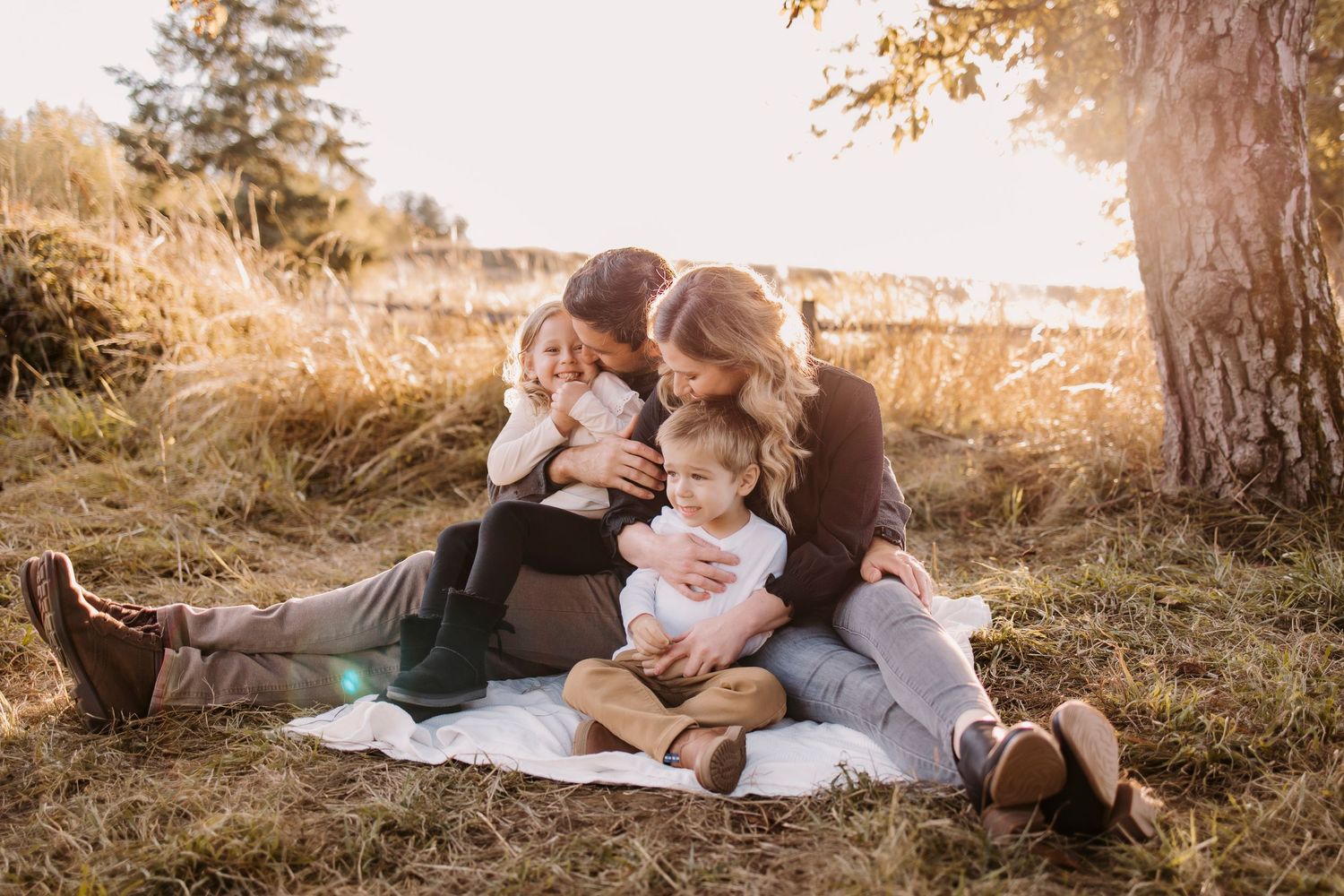 A family enjoys quality time together on a grassy hillside during golden hour.