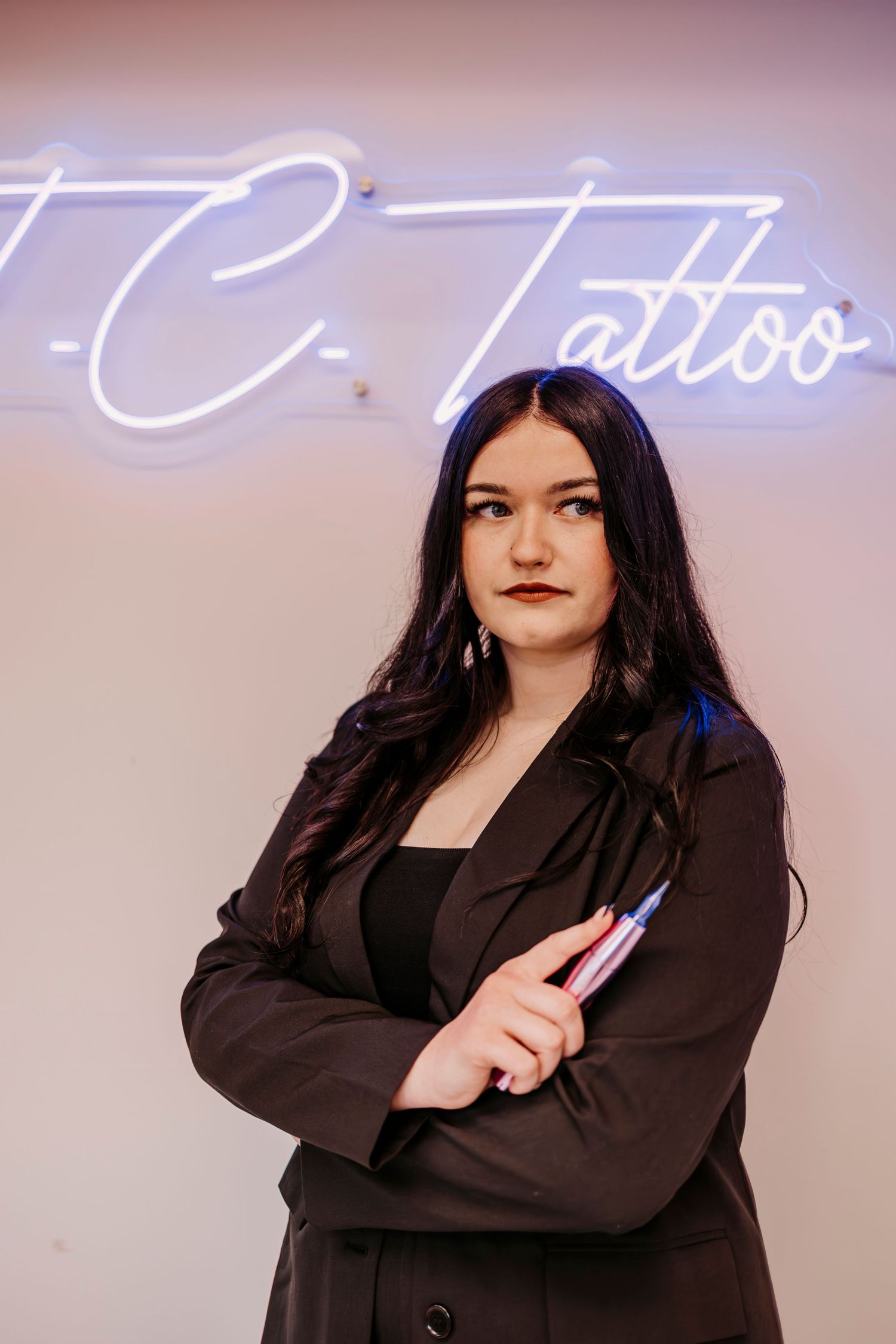 Professional photoshoot against illuminated wall with cursive neon text.