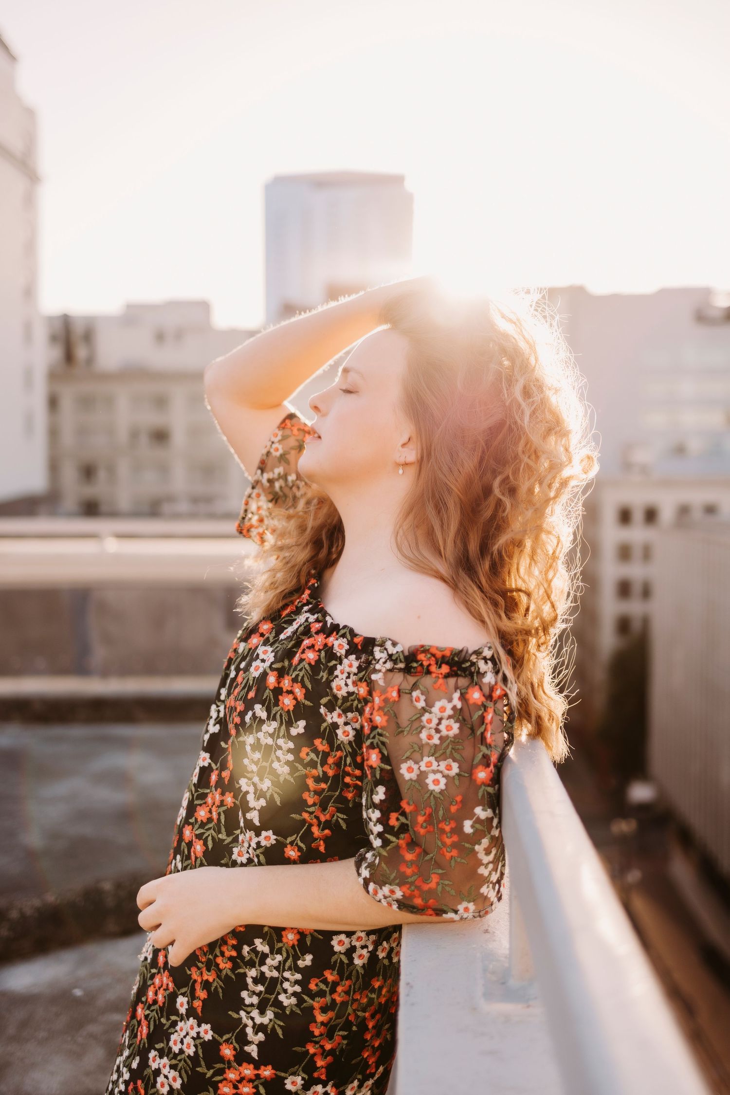 Floral dress photoshoot on urban rooftop during sunset.