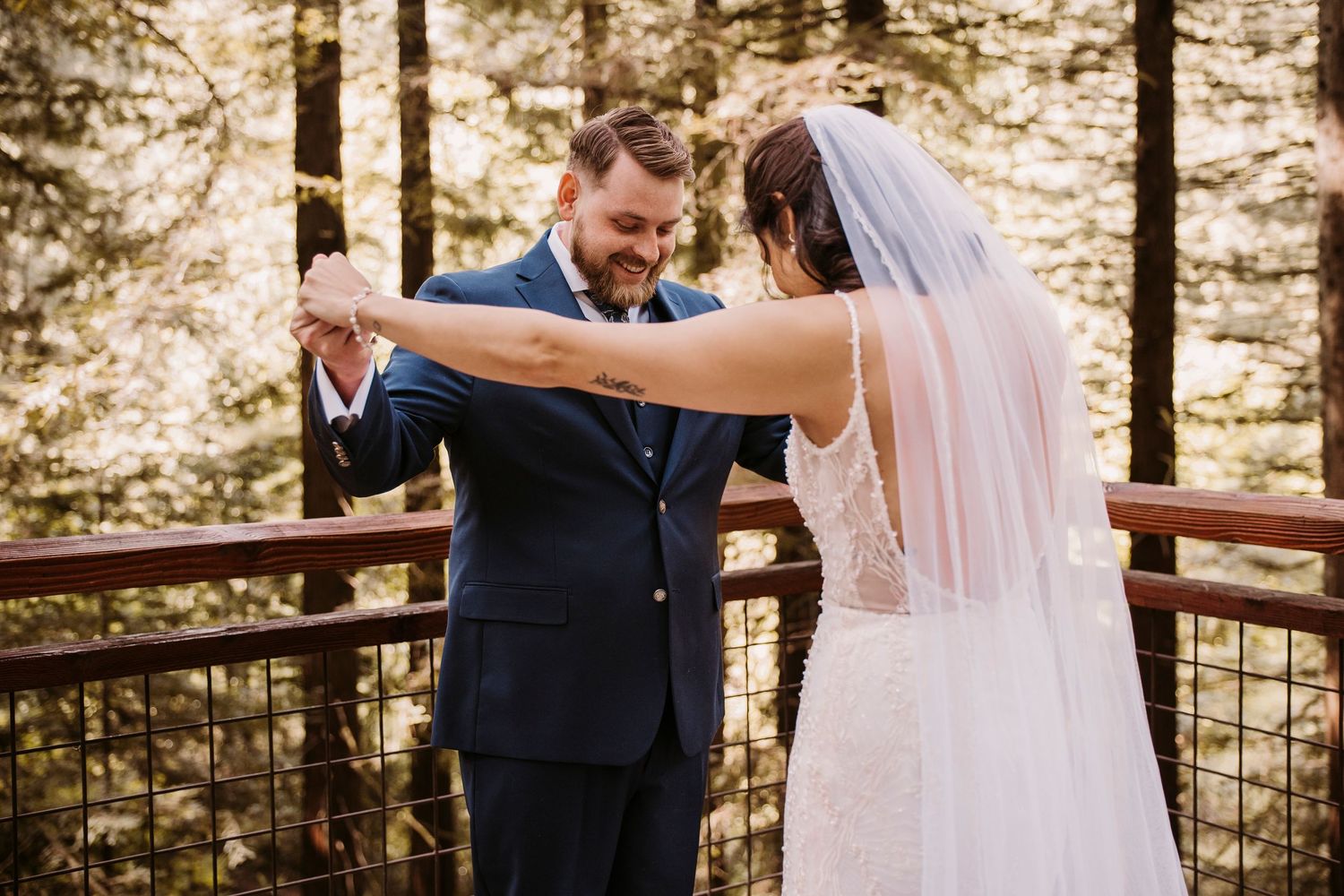 Wedding couple sharing intimate moment on wooden deck surrounded by forest.