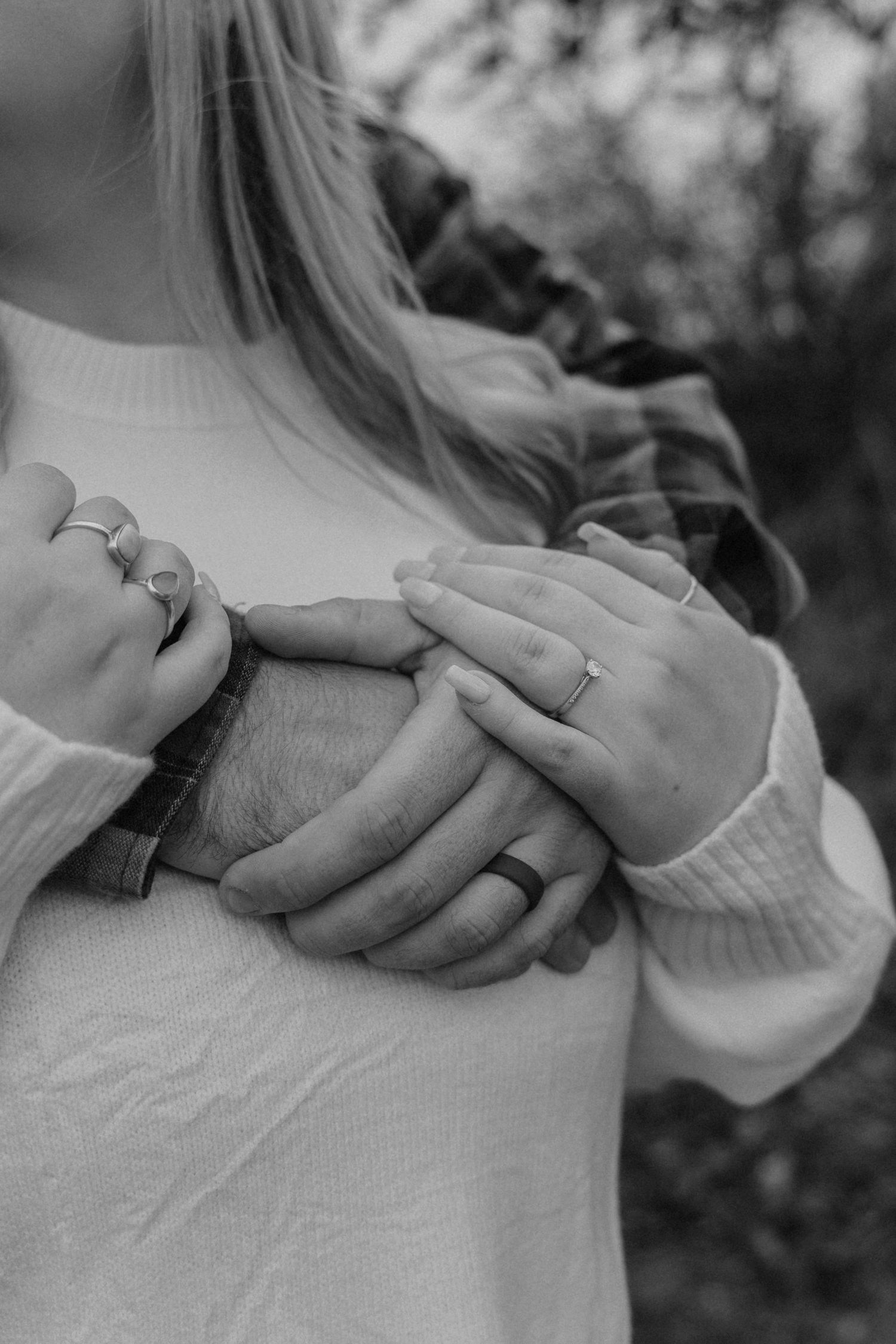 Black and white close-up photos of hands wearing wedding rings in a romantic engagement sequence.