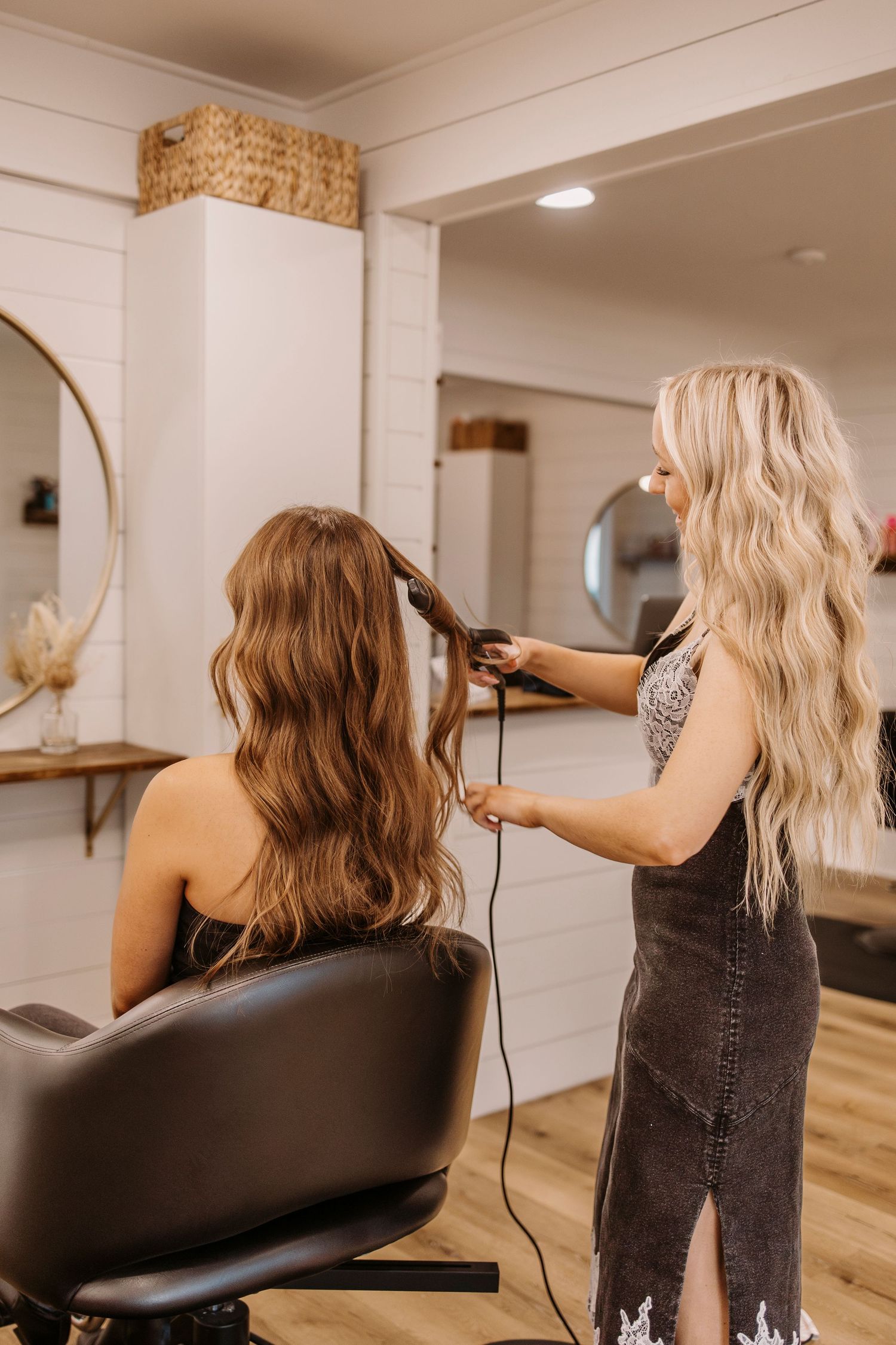 Hair styling session in modern salon with white walls and wooden floors.