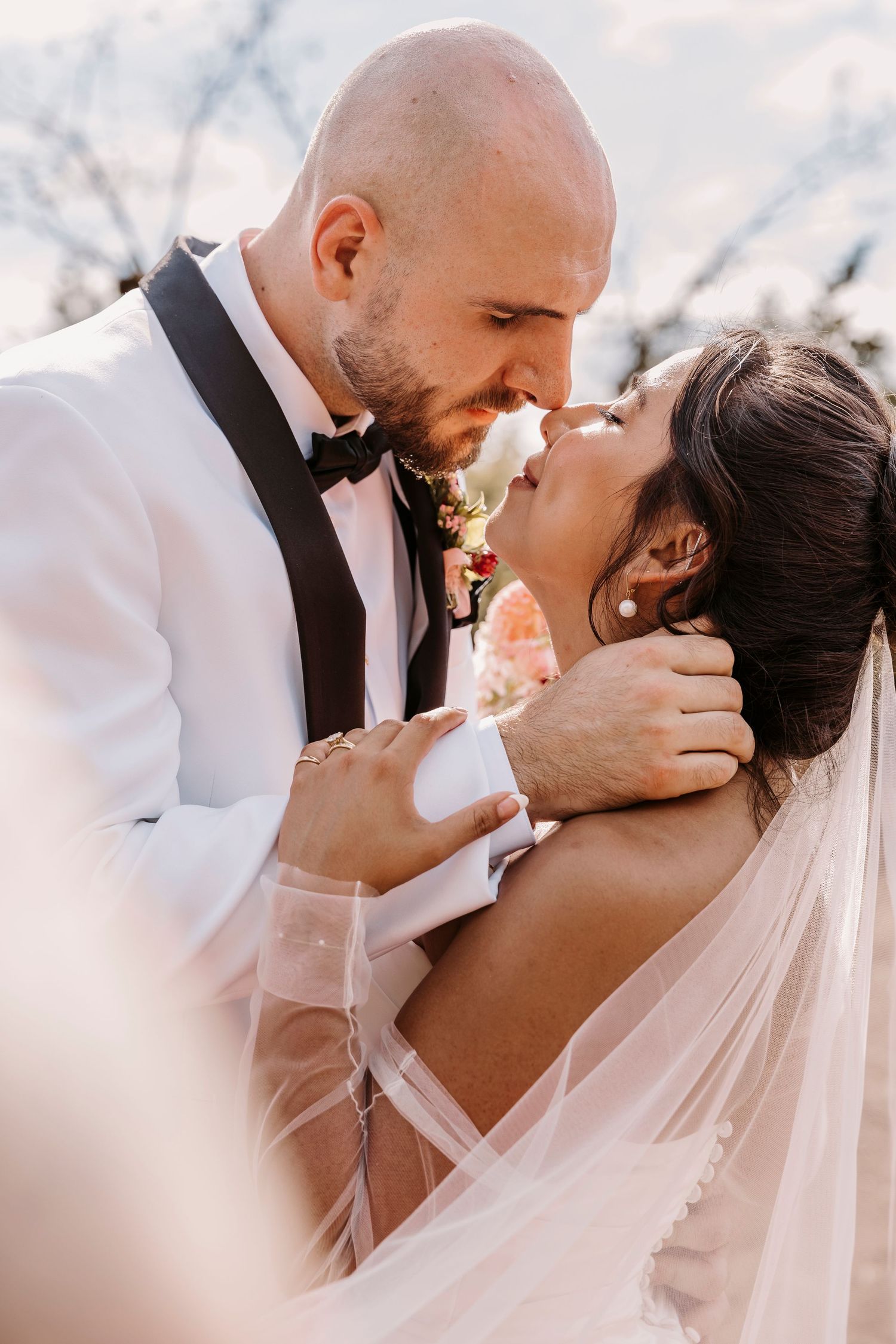 Intimate wedding portrait of newlyweds sharing a romantic moment outdoors.