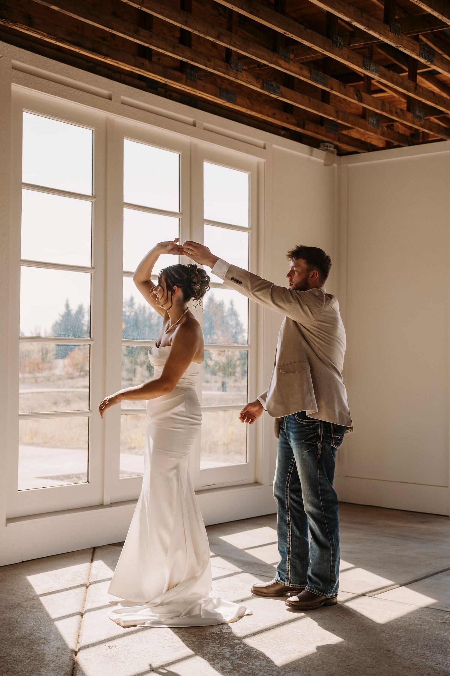 Sunlit room with exposed beams where wedding dress preparations are taking place.