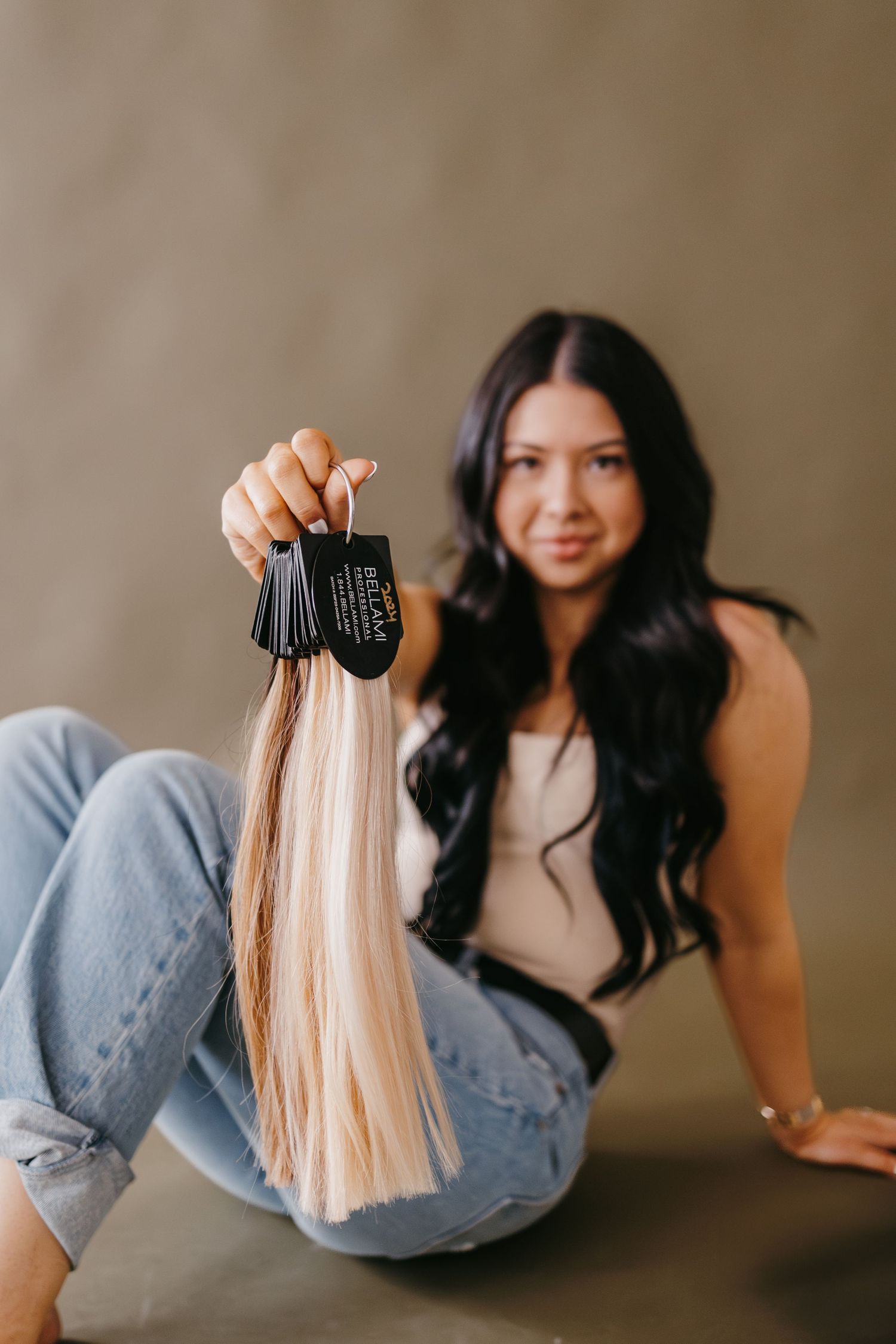 Hair styling demonstration showing blonde hair extensions against denim background.