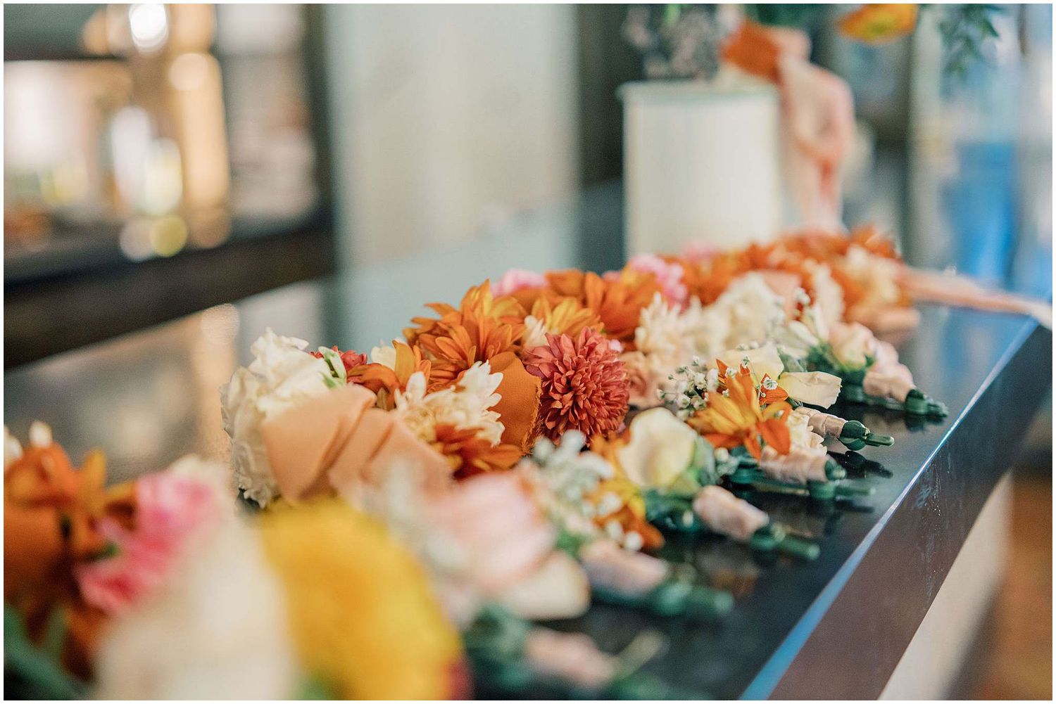 Peach and coral floral arrangements with greenery decorating a wedding reception table.
